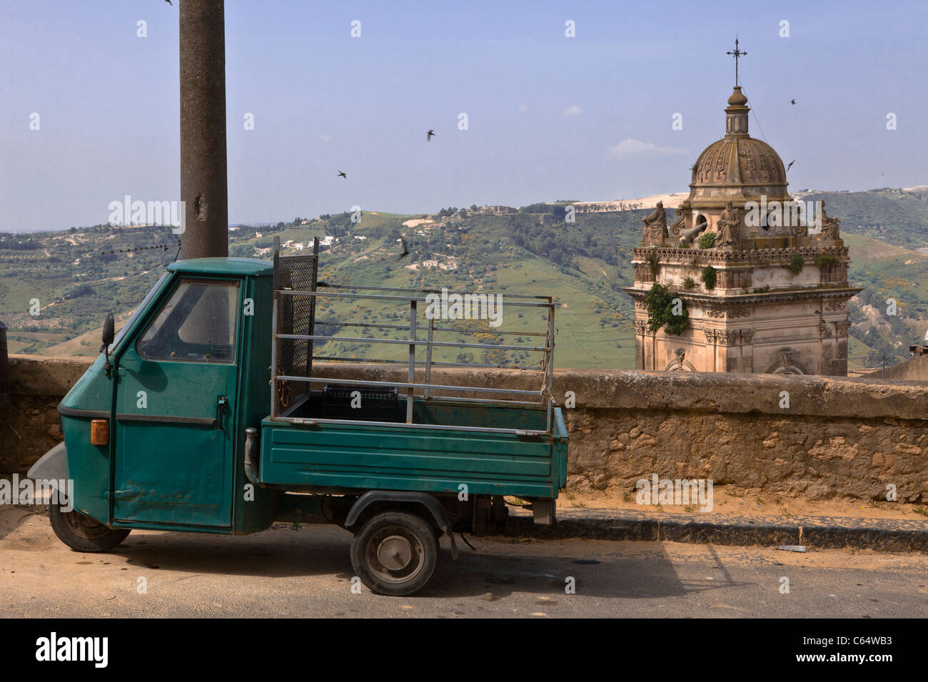Vendemmia verde per tre ruote ciclomotore Vespa parcheggiata nella parte anteriore di una cattedrale (Duomo) in Sicilia, costa mediterranea, Italia, Europa. Foto Stock