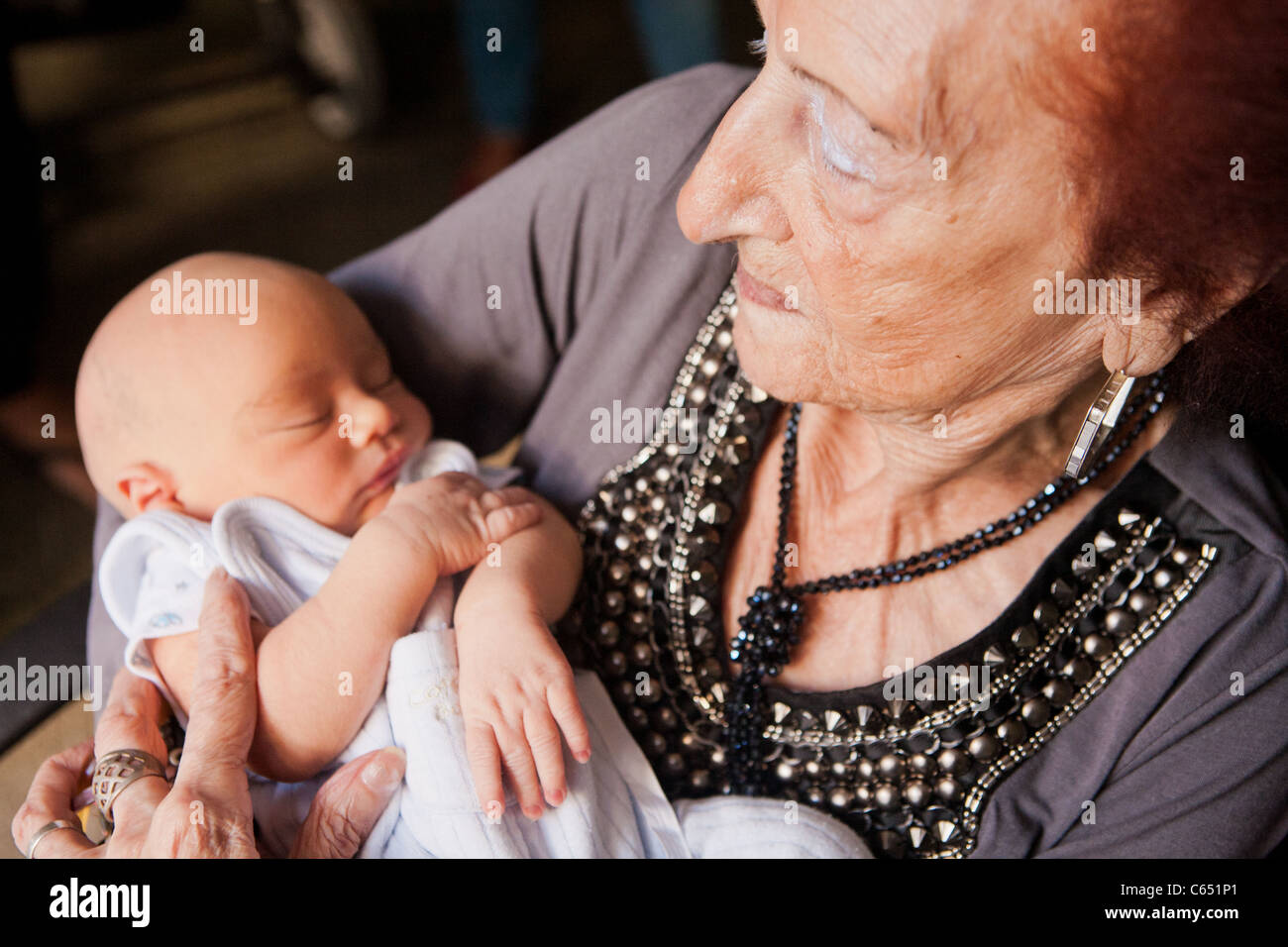 Una vecchia donna (bisnonna) azienda e il neonato pronipote. Foto Stock