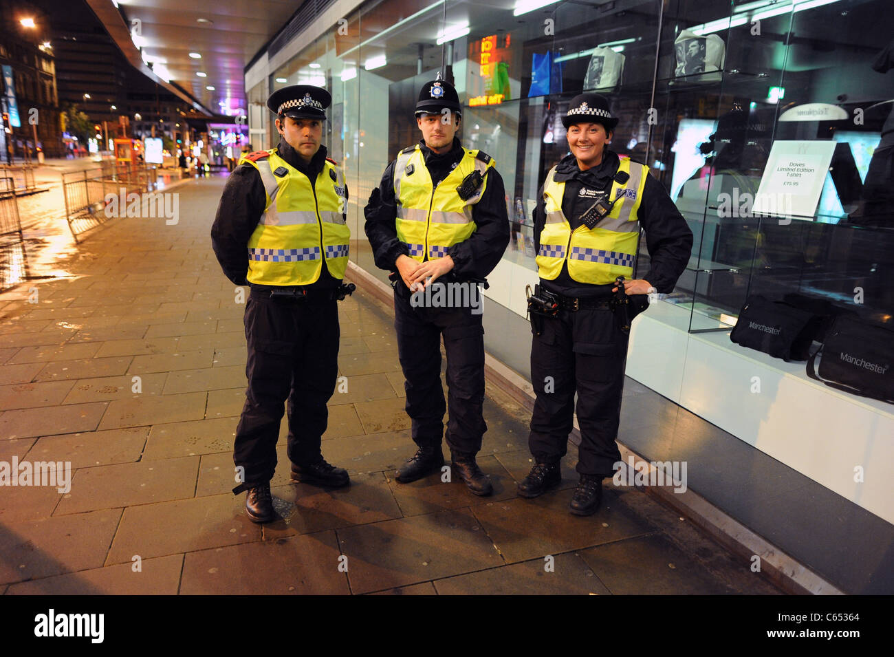 Tre agenti di polizia schierati in Manchester un giorno dopo il centro della città è stato colpito dal 2011 UK tumulti. Foto Stock