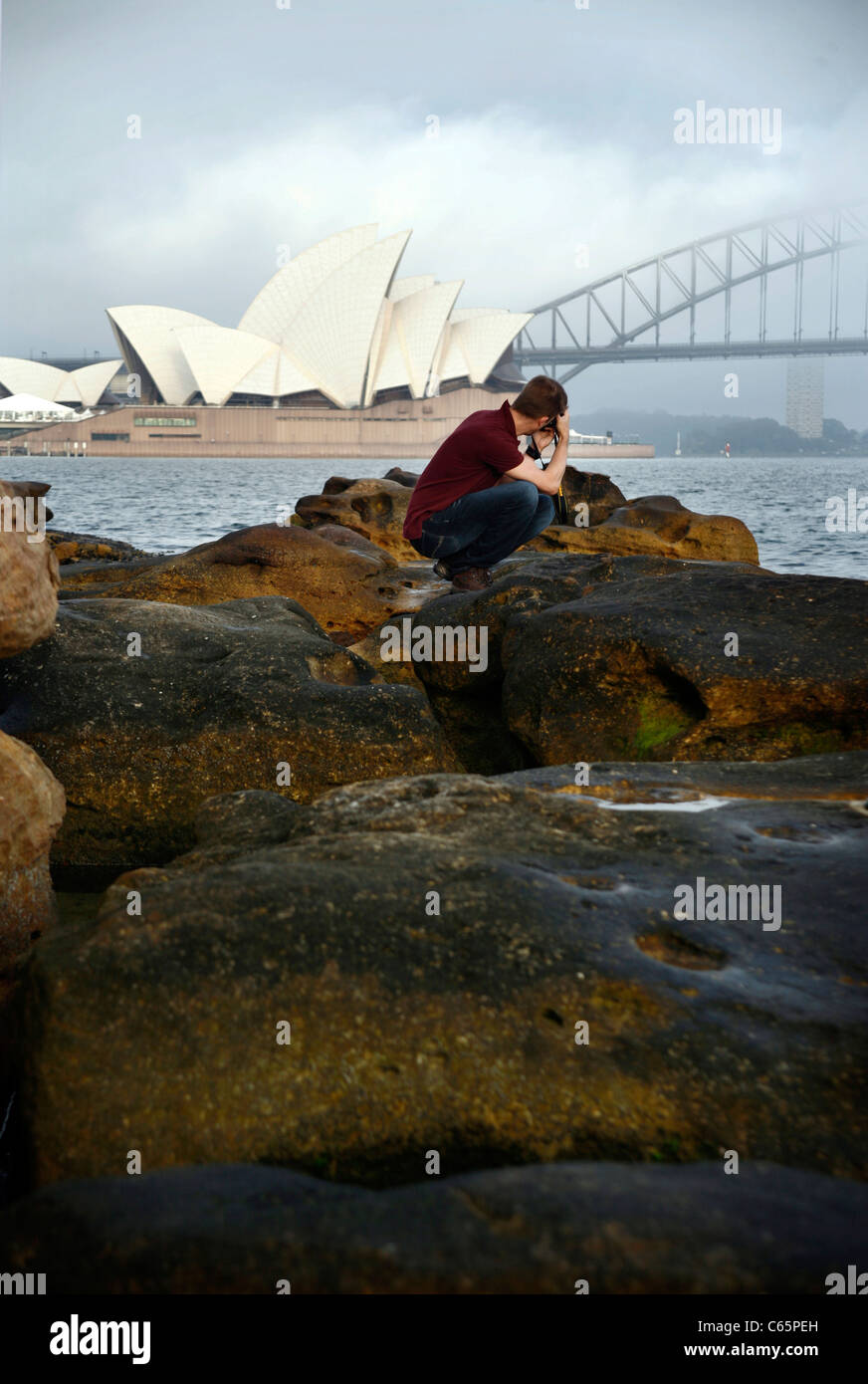 Un fotografo scatta una foto della Opera House di Sydney e il Sydney Harbour Bridge, la mattina presto Foto Stock