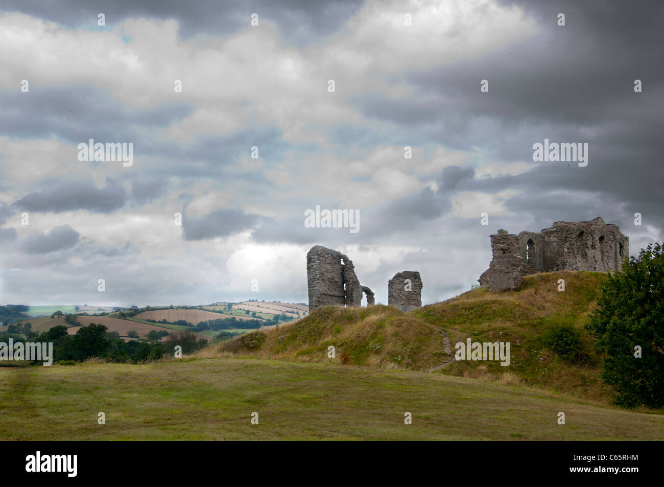 Il castello di Clun con nuvole scure con le colline del confine gallese dietro Foto Stock