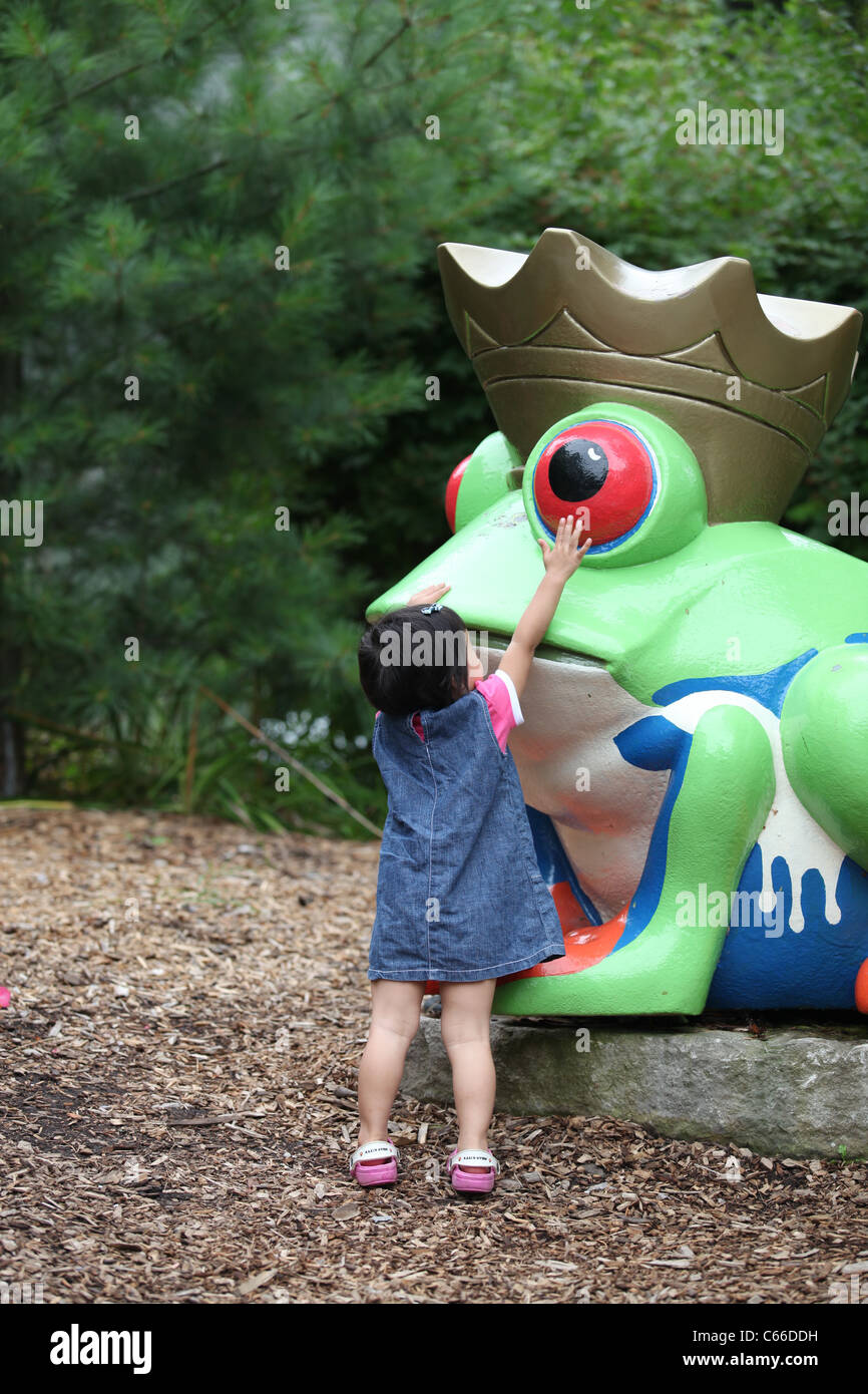 Ragazza che gioca con la rana nella Storybook park a Londra, Ontario, Canada Foto Stock