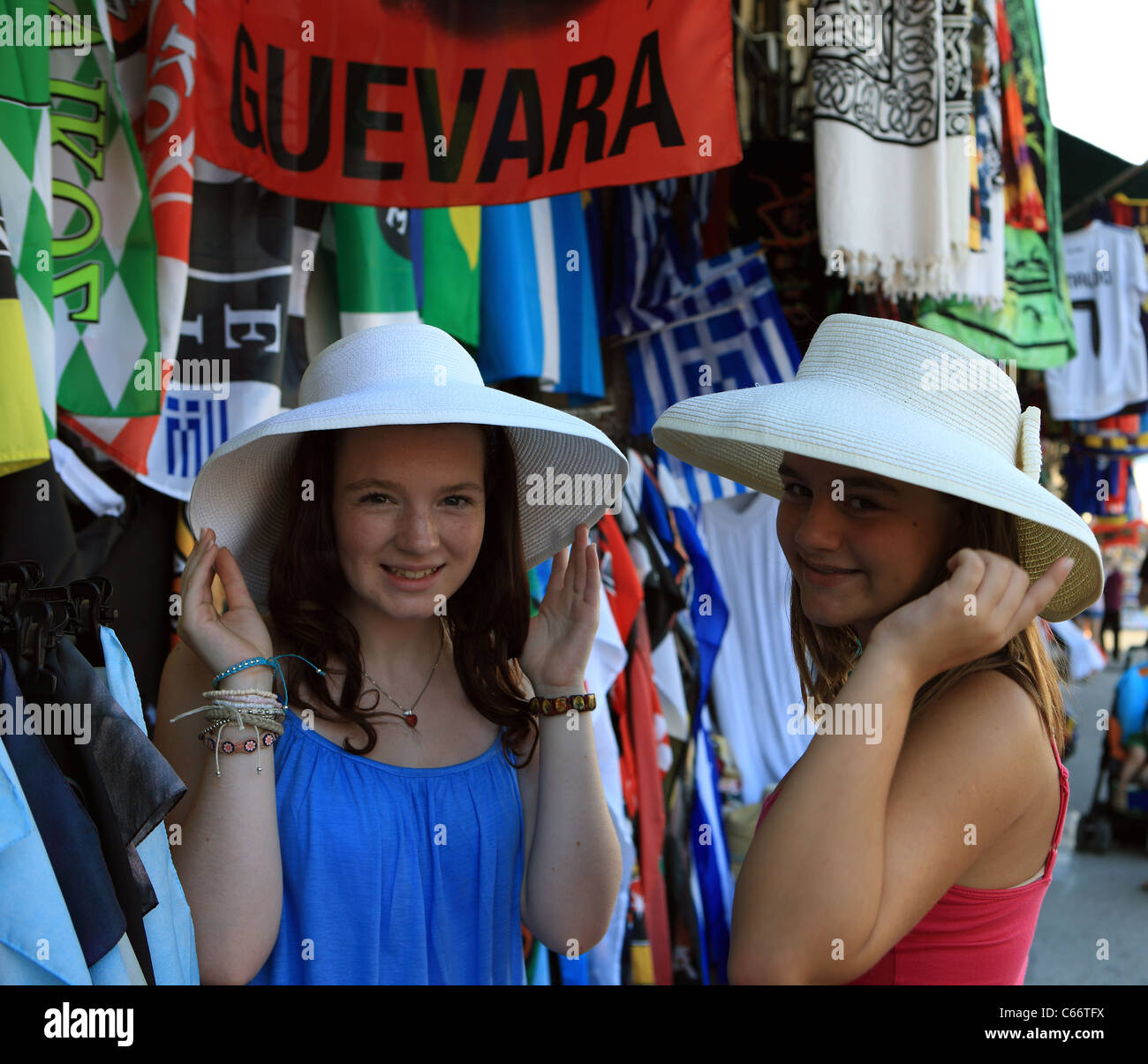 Quartiere Plaka di Atene in Grecia. Le ragazze adolescenti avendo divertimento cercando su cappelli in uno dei tanti negozi di souvenir in zona. Foto Stock