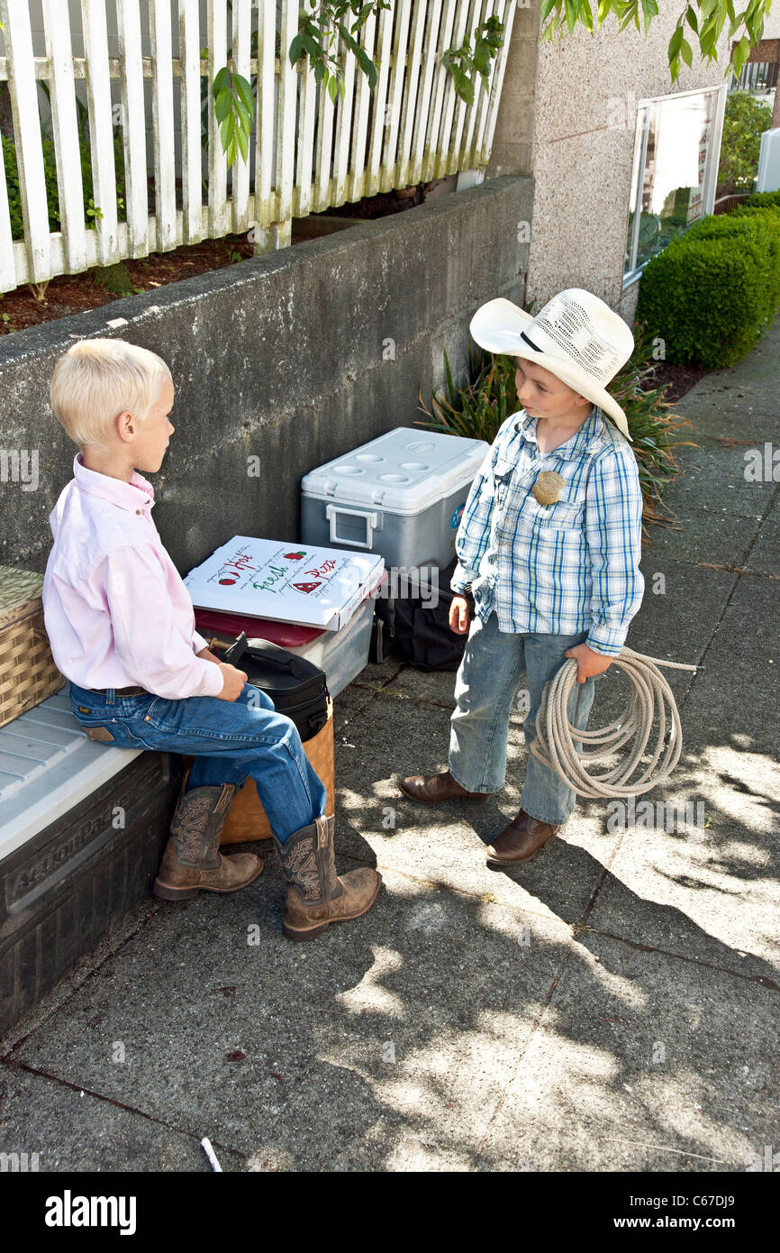Un giovanissimo cowboy in autentica western dress holding corda avvolto a spirale discute le funi di bobinatura con il suo fratello più anziano Edmonds Foto Stock