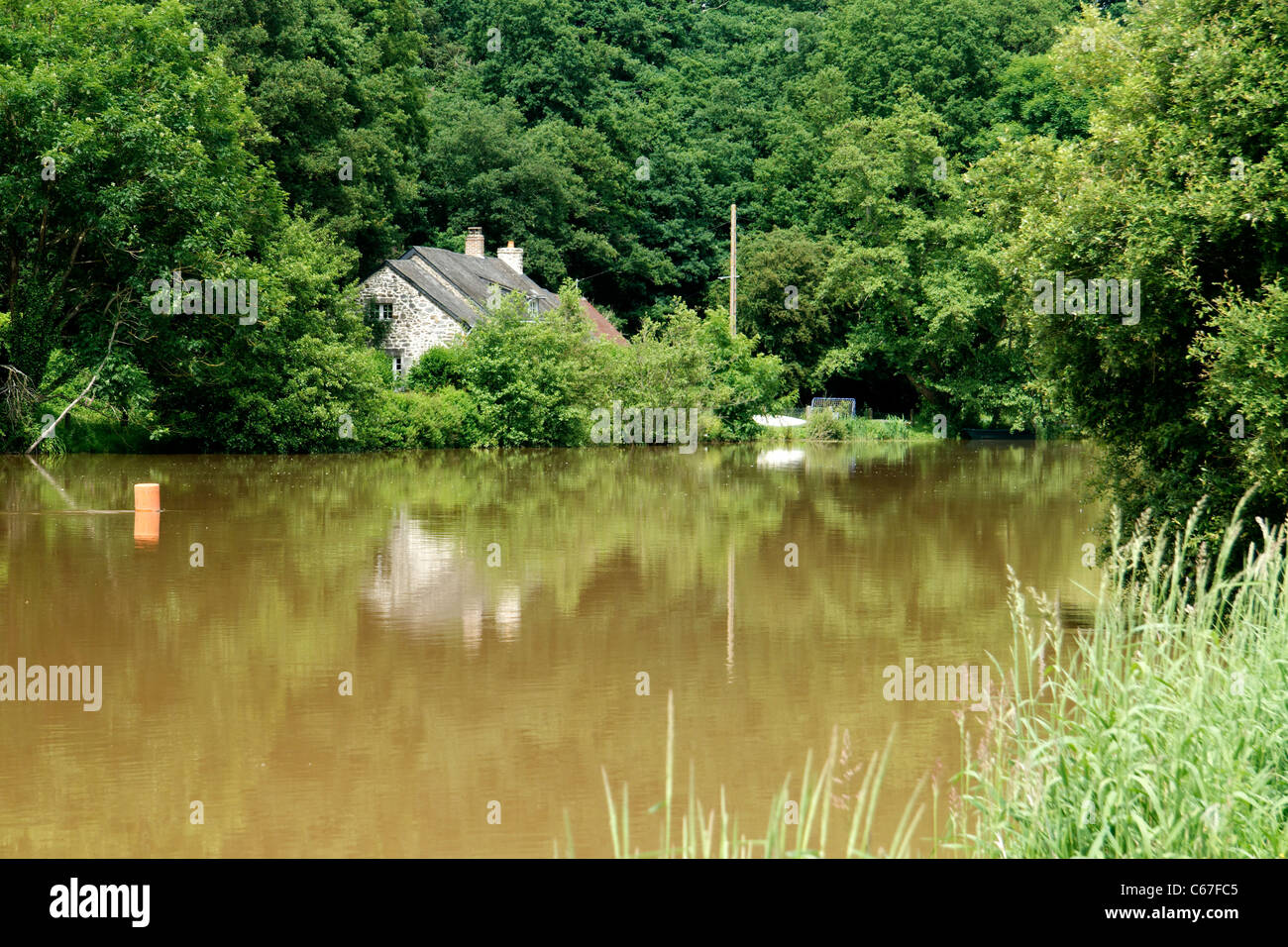 Casa sul fiume, il fiume a pieno volume dopo la tempesta di pioggia, la Mayenne (Mayenne, Pays de la Loire, Francia). Foto Stock