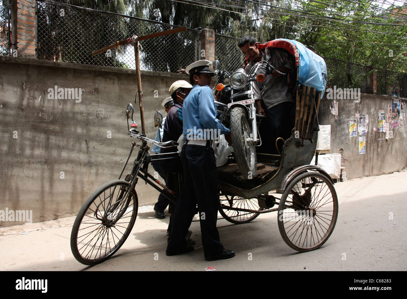 Assistere la polizia nepalese rider rickshaw per rimuovere il moto dal suo triciclo Foto Stock