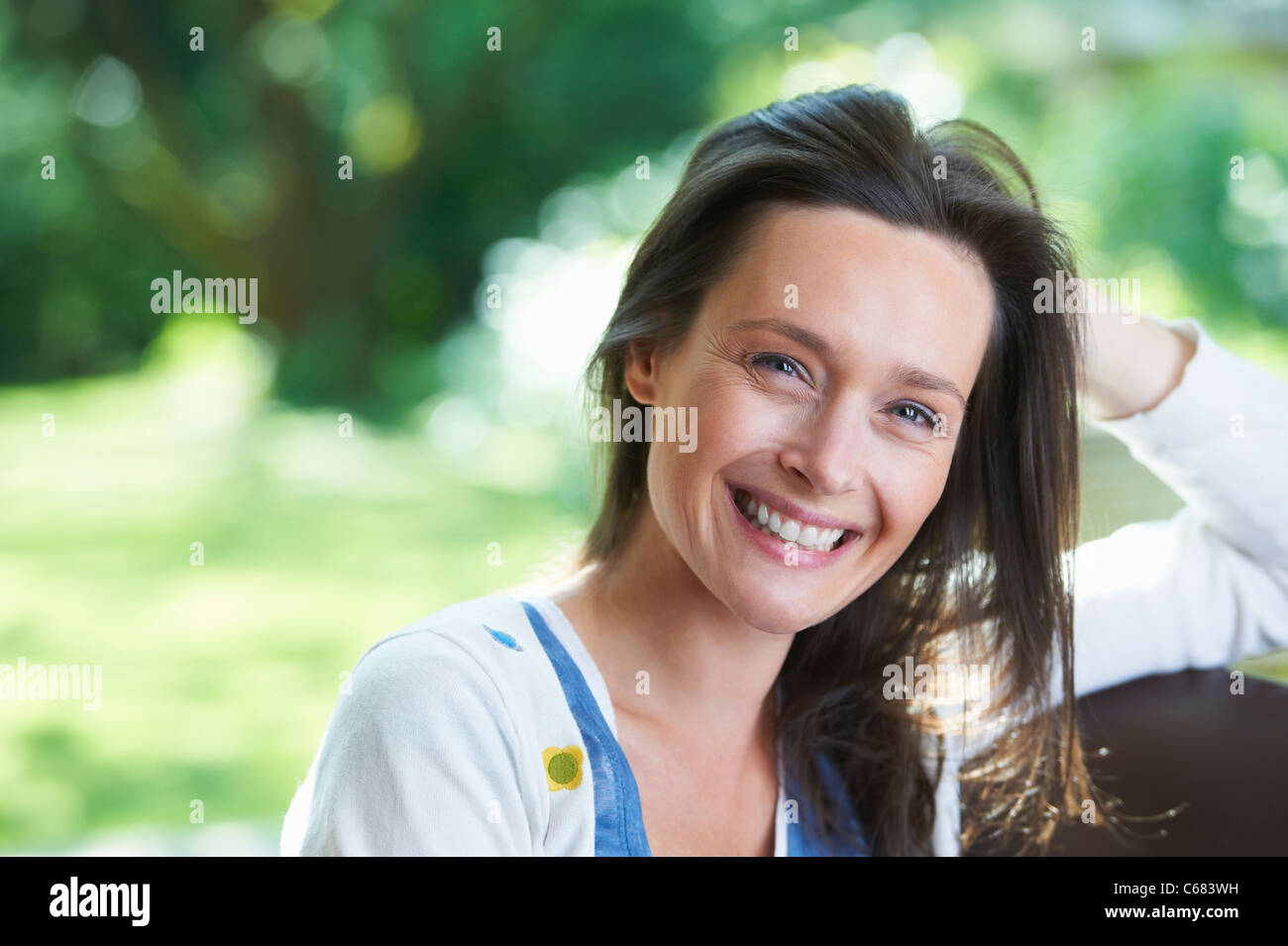 Donna sorridente seduti all'aperto Foto Stock