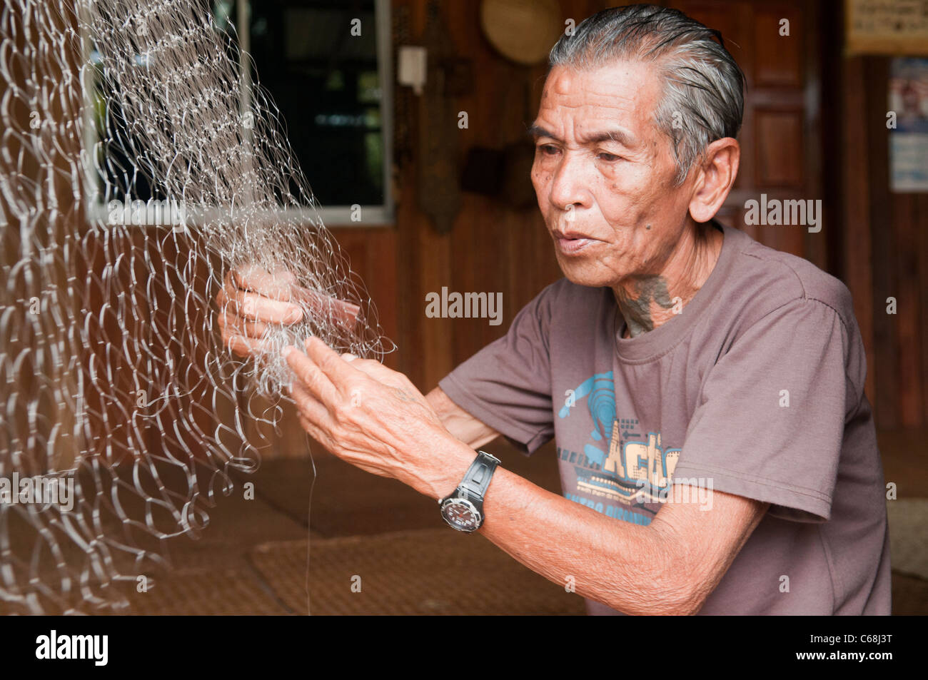 Iban longhouse chief mende sue reti da pesca al Nanga Sumpa longhouse nel Sarawak, Borneo Malaysia Foto Stock