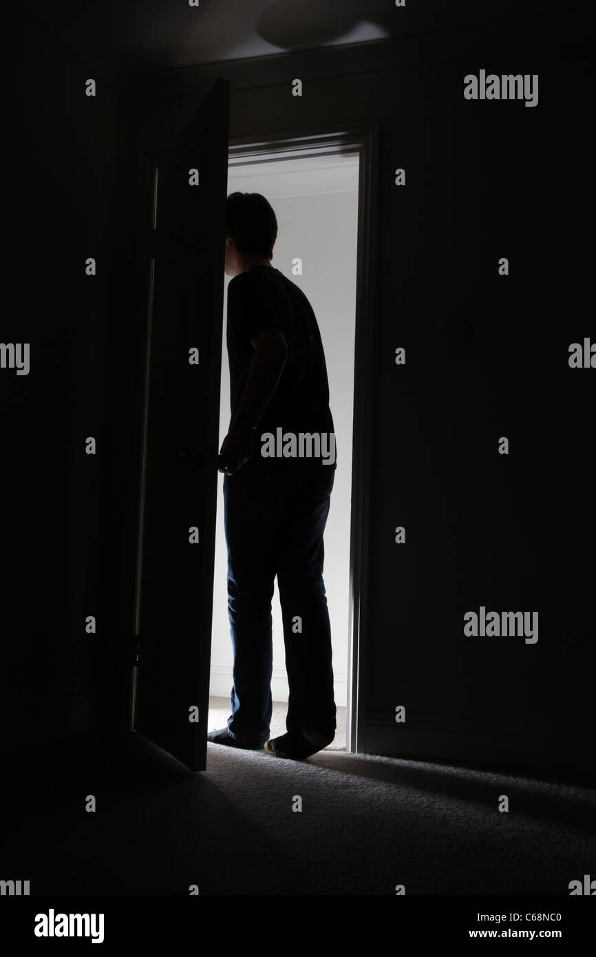 Silhouette di un uomo di lasciare una stanza buia. Foto Stock