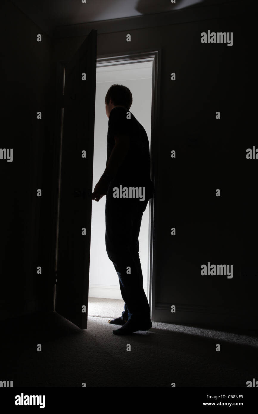 Silhouette di un uomo di lasciare una stanza buia. Foto Stock