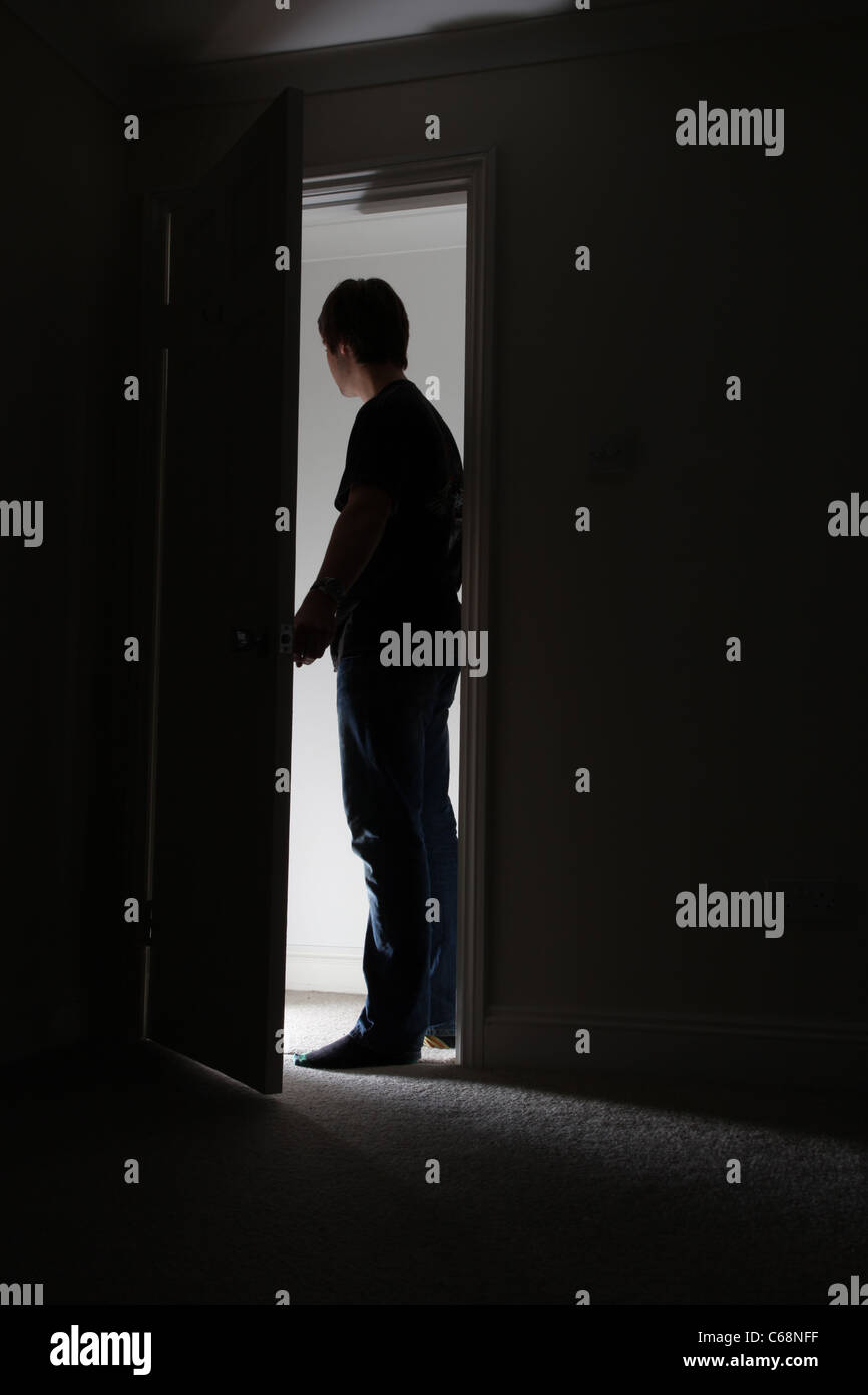 Silhouette di un uomo di lasciare una stanza buia. Foto Stock
