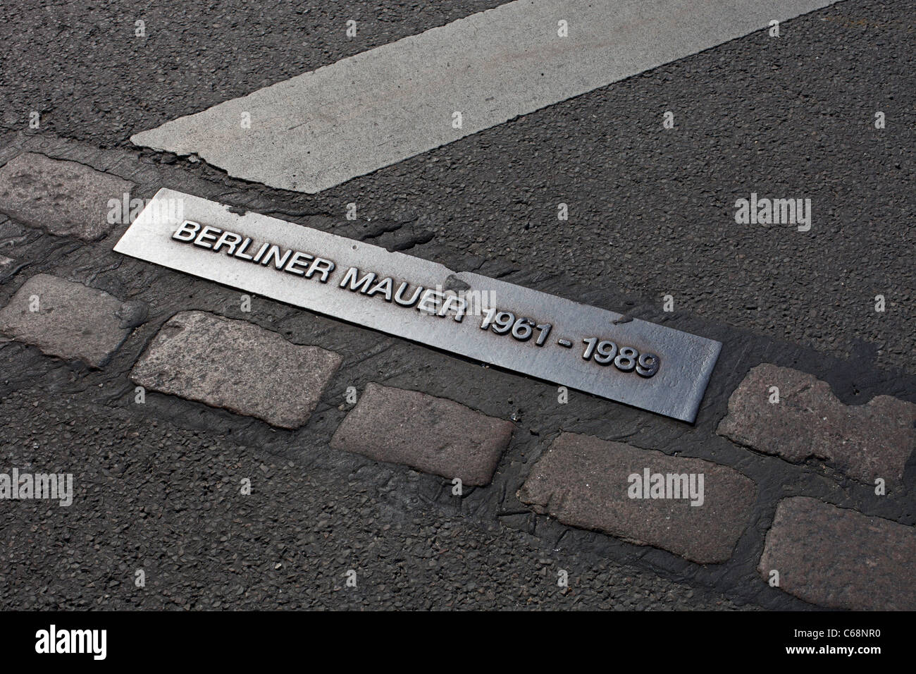 Una targa e pietre di pavimentazione sulla strada vicino alla porta di Brandeburgo segnano la posizione dell'ex muro che divise Berlino durante la Guerra fredda. Foto Stock
