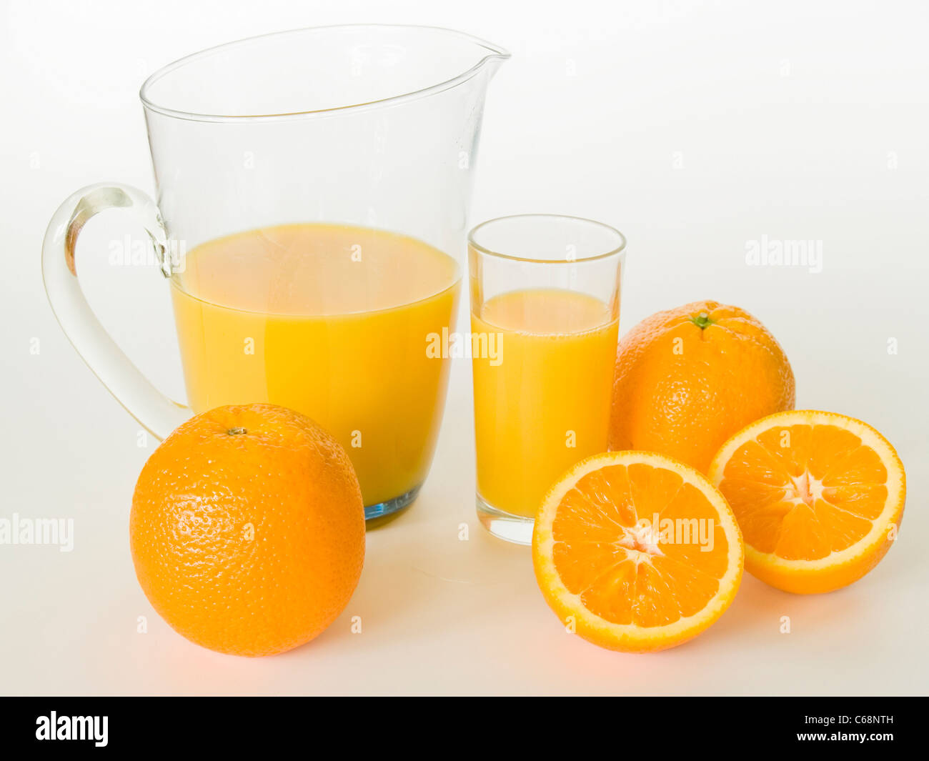 Una caraffa di vetro e con un bicchiere di succo di arancia, di fronte sono le arance Foto Stock