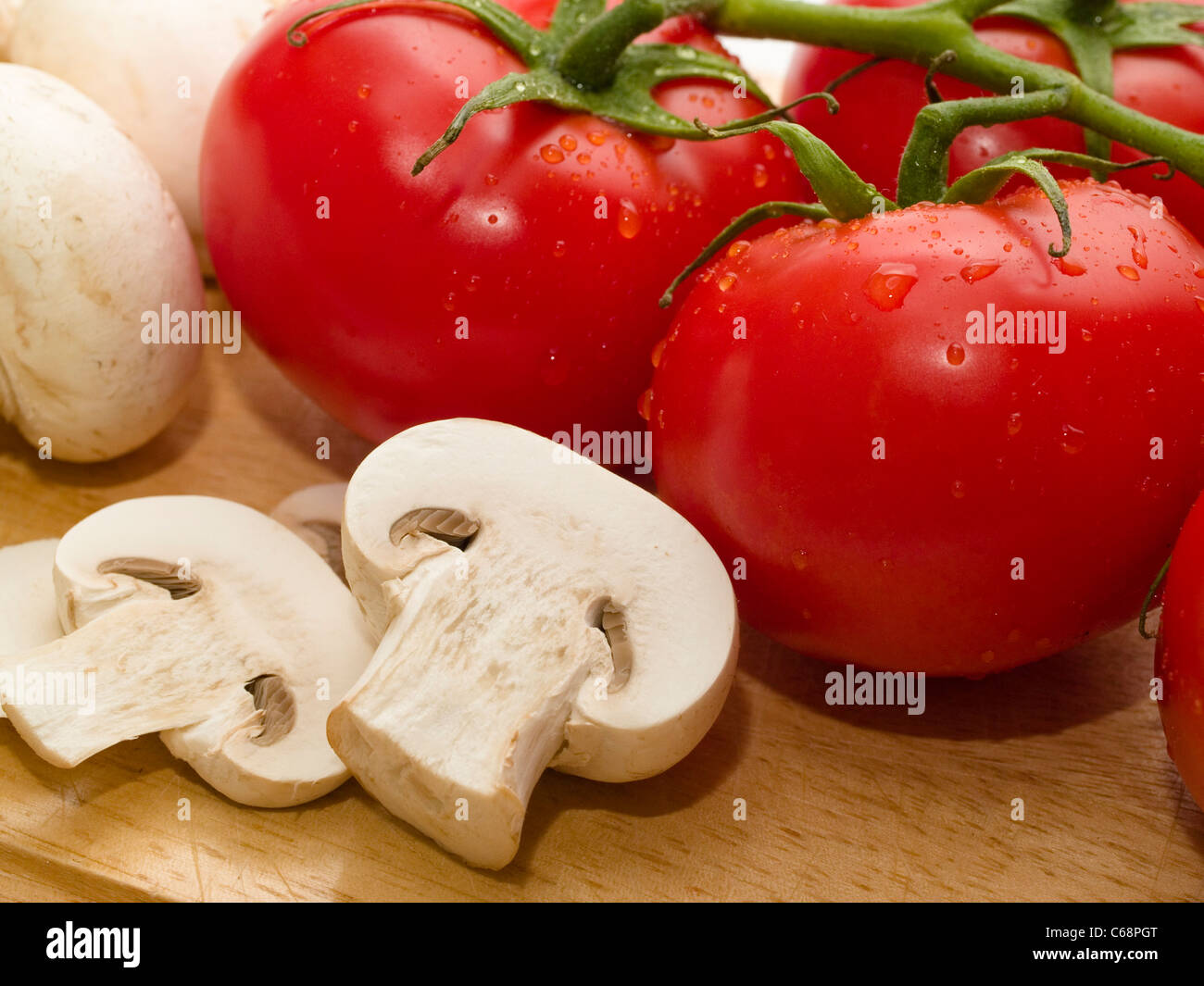 Auf einem Holzbrett Chamignons liegen und Tomaten | su un pannello di legno sono i funghi e i pomodori Foto Stock