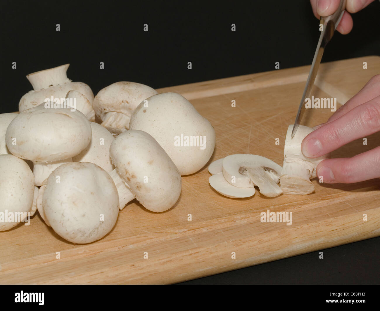 Gli champignon werden Mit einem Messer auf einem Holzbrett geschnitten | Funghi sarà tagliata con un coltello su un pannello di legno Foto Stock