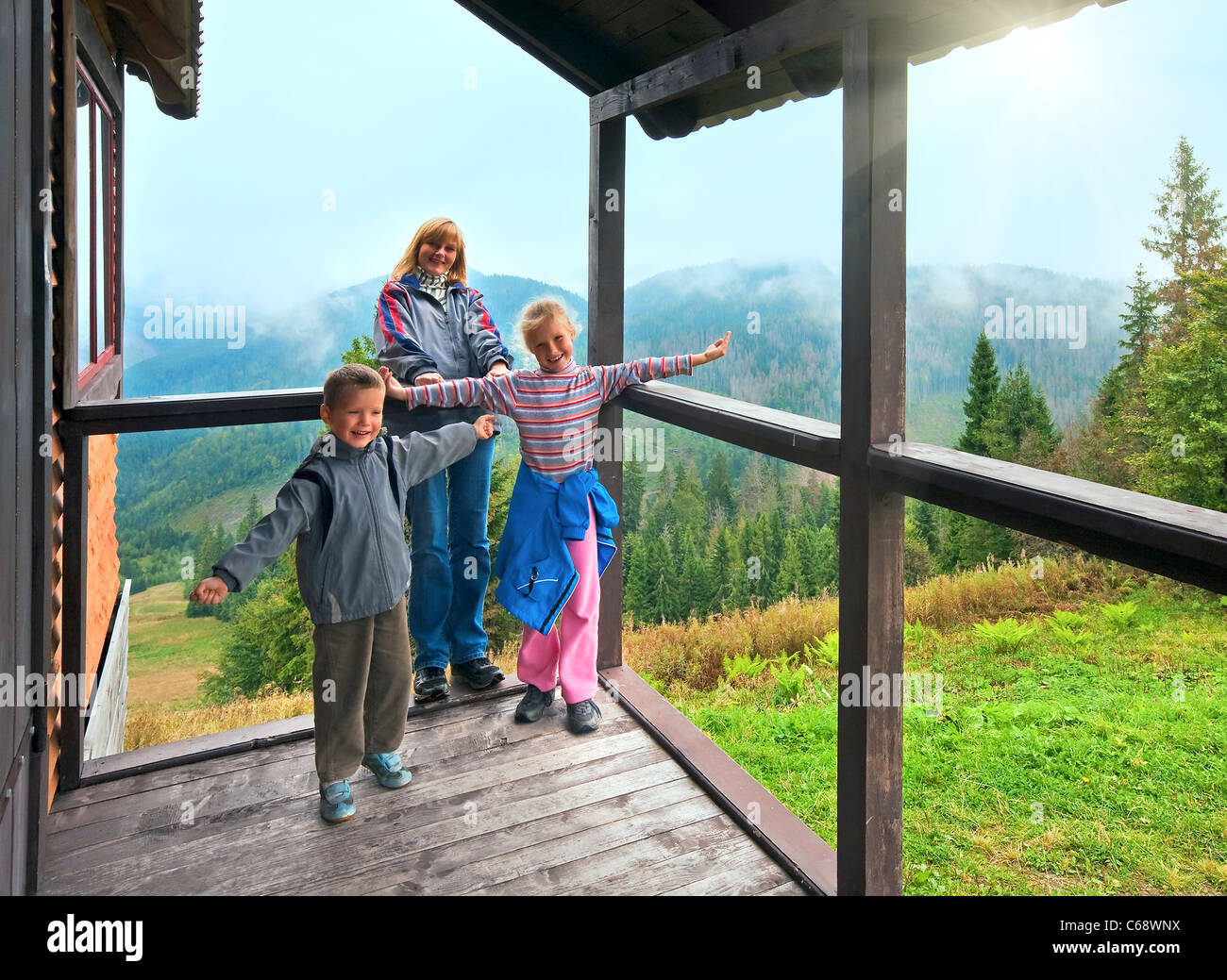 Famiglia in cottage di legno portico sulla montagna hill top e sole Foto Stock