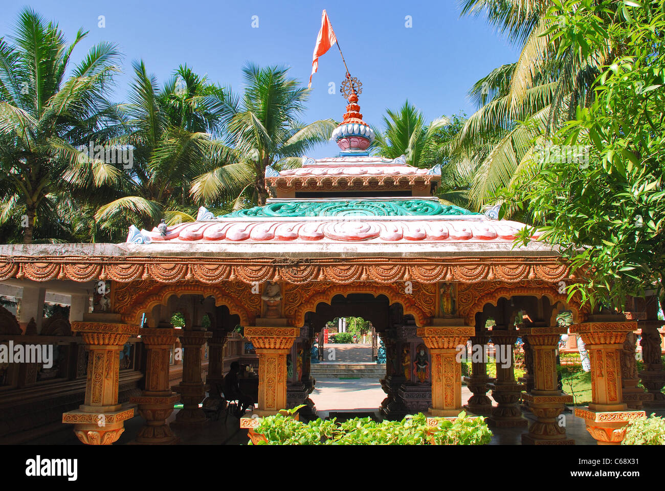 Un tempio dedicato al dio di Ram, dipinte con colori luminosi, circondato da alberi di noce di cocco, su uno sfondo di colore blu cielo Foto Stock