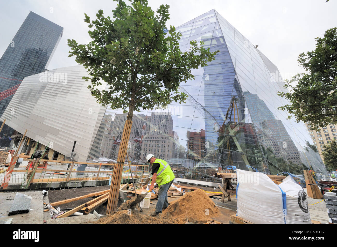 Un lavoratore edile presso il World Trade Center del sito con il National September 11 Museum in costruzione dietro di lui. Foto Stock