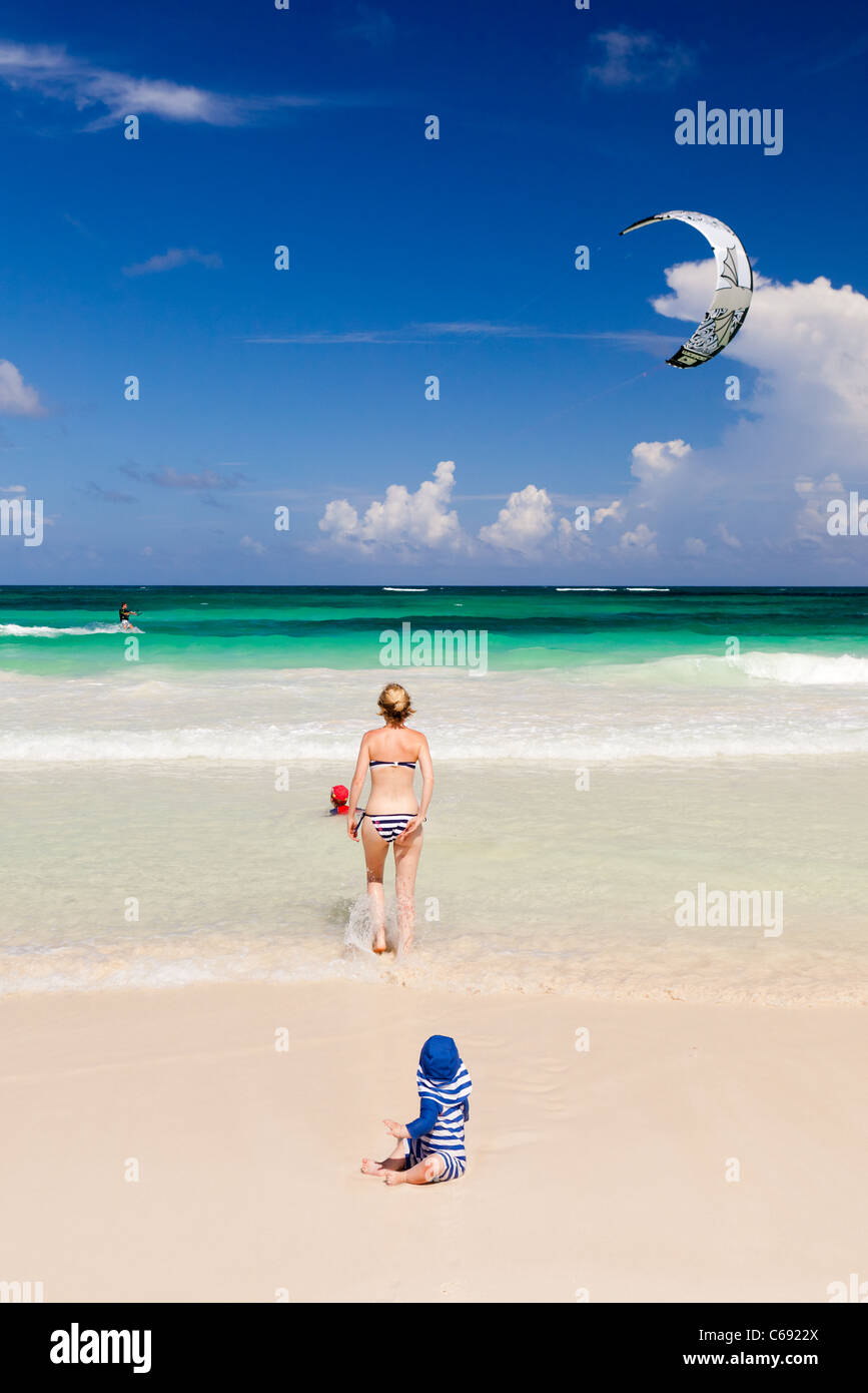 Una giovane famiglia guardando un kitesurfer sulla spiaggia, Tulum, Messico Foto Stock