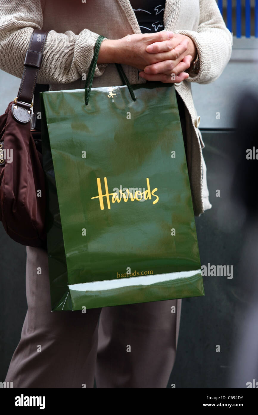 Un Harrods shopping bag essendo portato da un acquirente Foto stock - Alamy