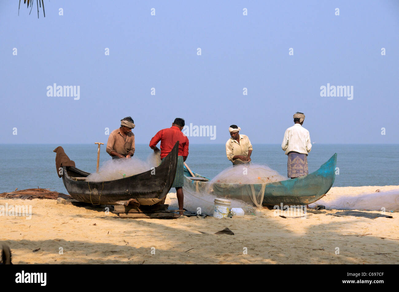 Ordinamento dei pescatori reti da pesca sulla spiaggia Marari Kerala India del Sud Foto Stock