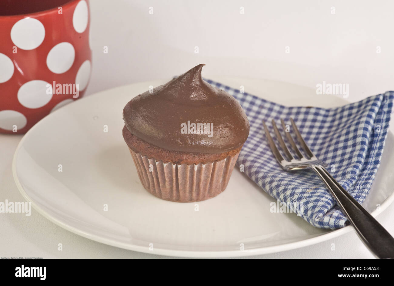 Muffin al cioccolato bianco sulla piastra con coppa di rosso e uno blu gingham igienico Foto Stock