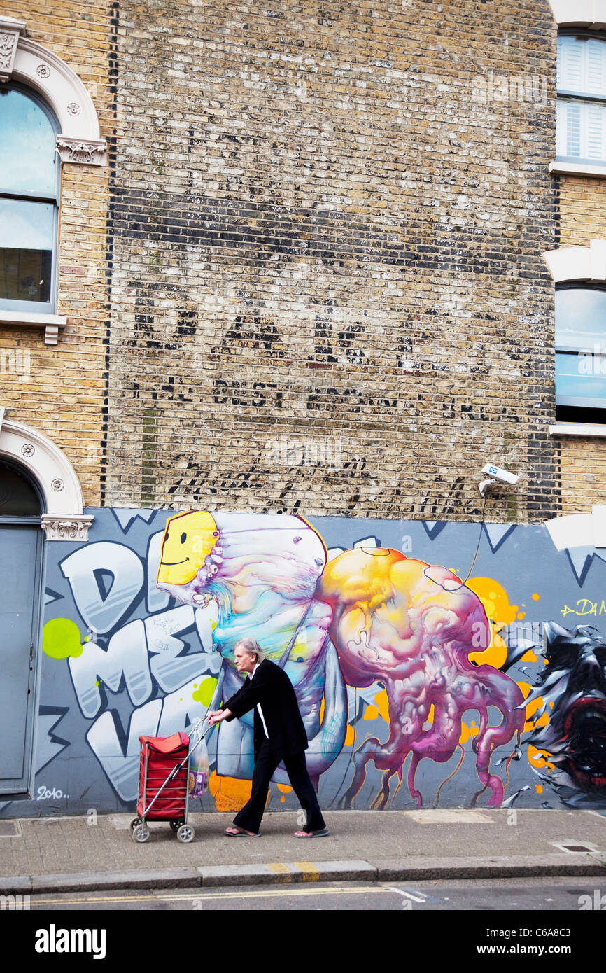 Street a Londra Sud, una parete con gli storici resti di una vecchia pubblicità segno è contrastato da alcuni moderni graffiti street art Foto Stock