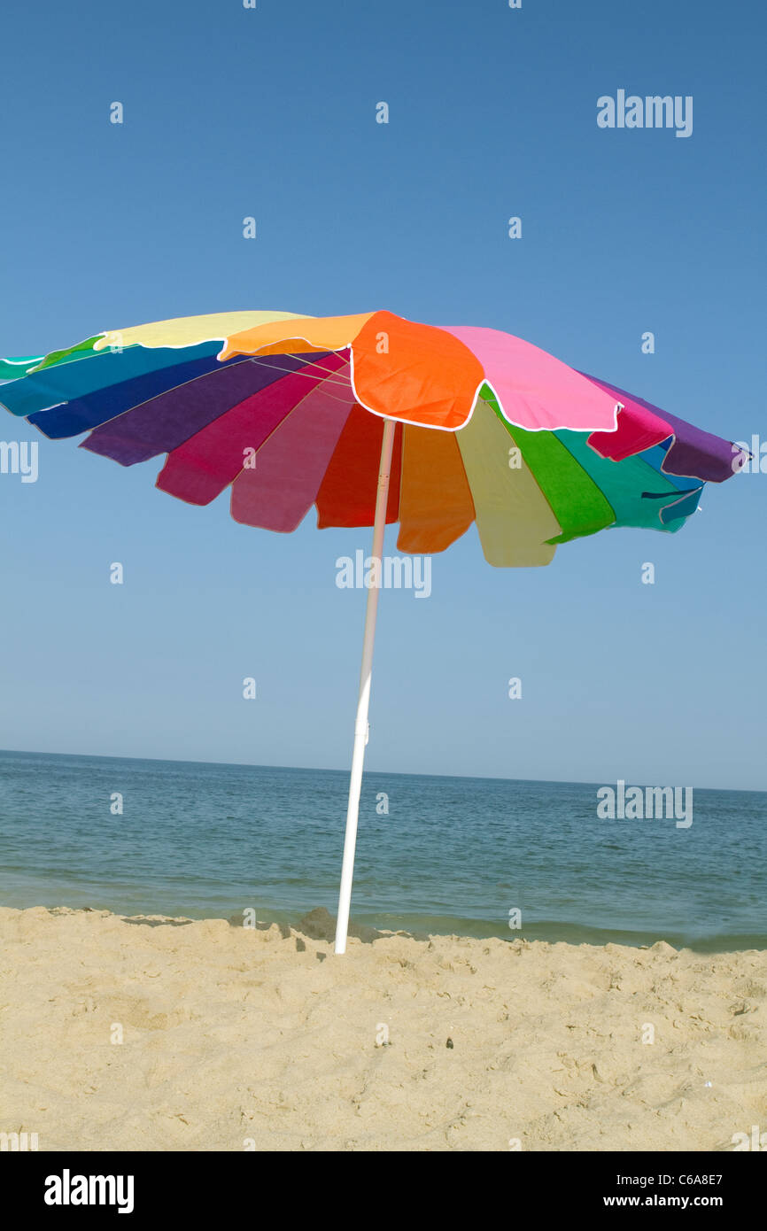 Un arcobaleno ombrellone in spiaggia Foto Stock