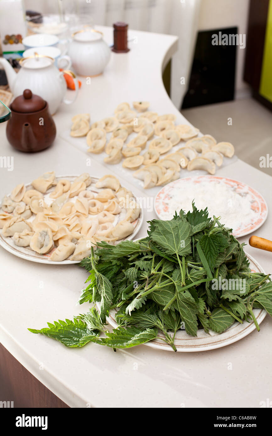 Canederli di carne da ortica. Ravioli di ortica su tavolo e foglie di ortica nella piastra. Cucina interno Foto Stock