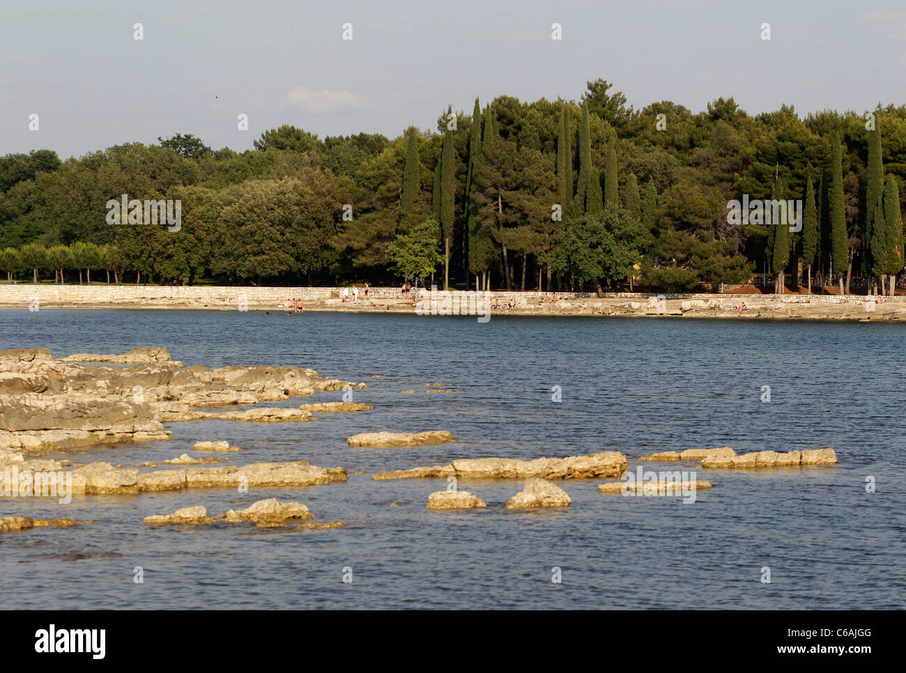 Spiaggia rocciosa della baia a bordo di una foresta a Umag, Croazia, Foto Stock