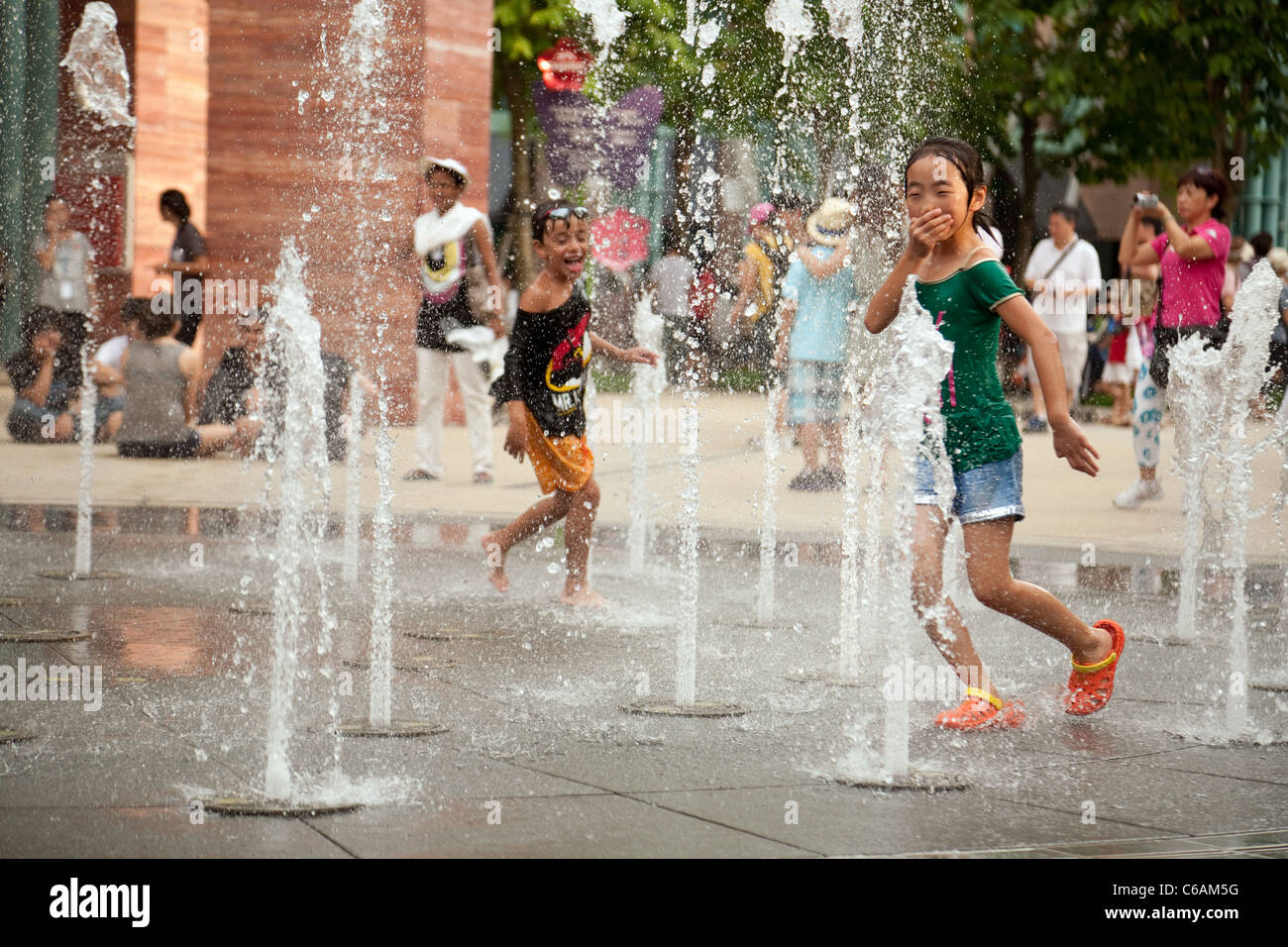 Giovani asiatici di bambini che giocano con le fontane, Universal Studios l'isola di Sentosa, Singapore Foto Stock
