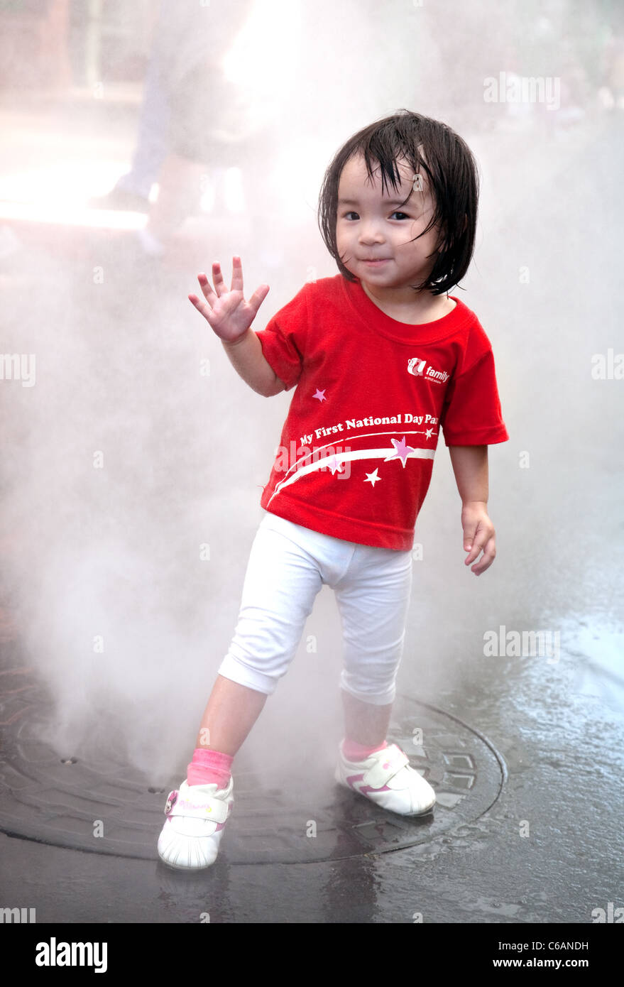 Un bambino di Singapore in giornata nazionale shirt giocando con le fontane, Universal Studios l'isola di Sentosa, Singapore Foto Stock