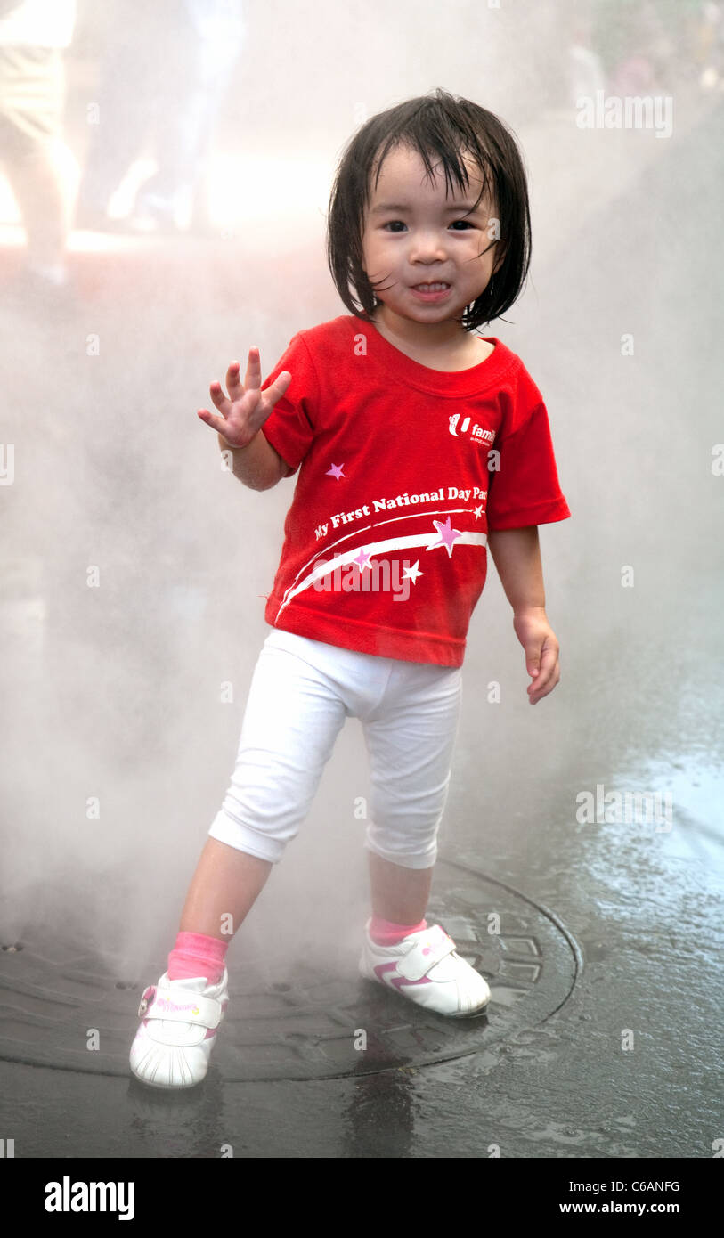 Un bambino di Singapore in giornata nazionale shirt giocando con le fontane, Universal Studios l'isola di Sentosa, Singapore Foto Stock