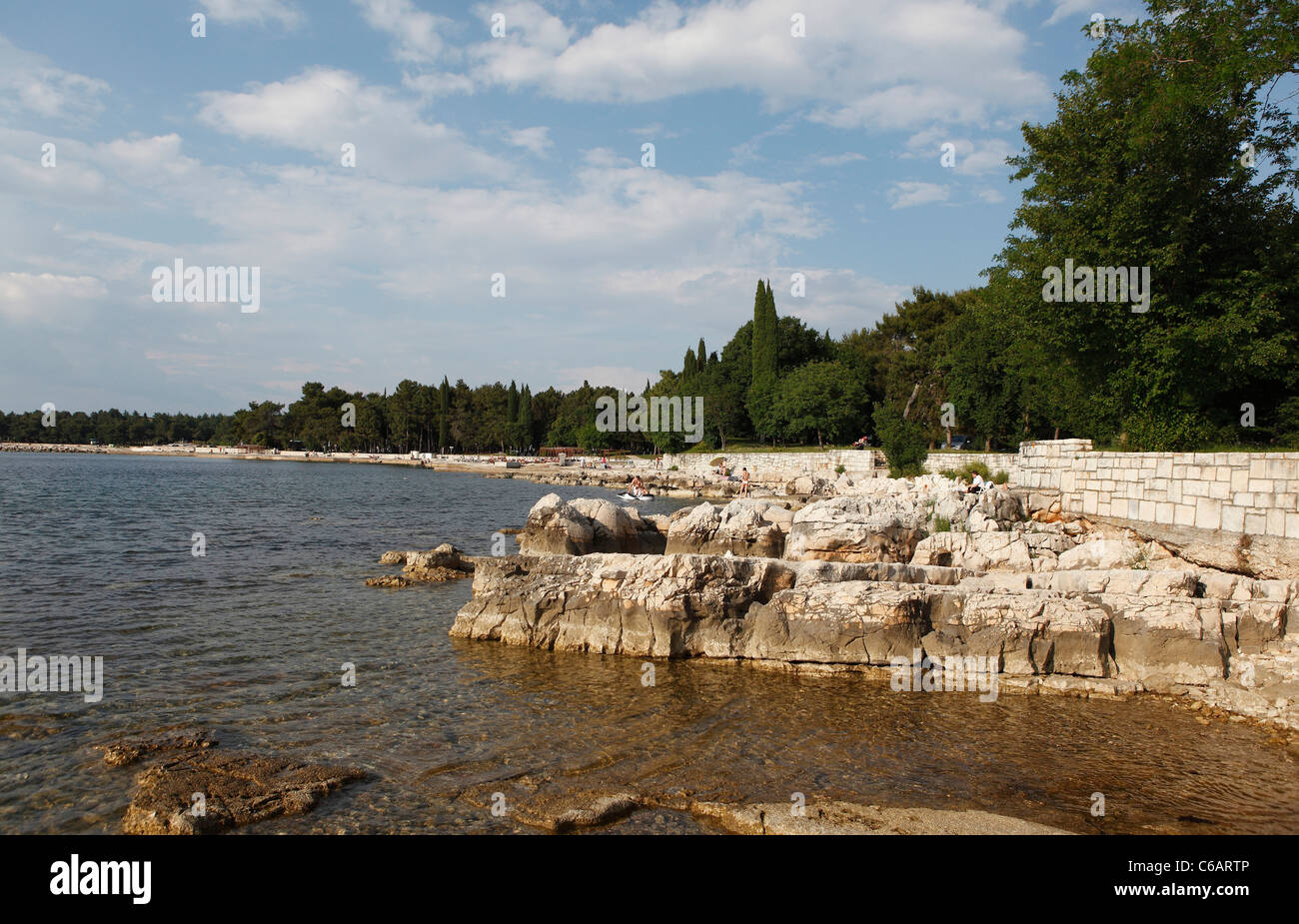 Spiaggia rocciosa della baia a bordo di una foresta a Umag, Croazia, Foto Stock