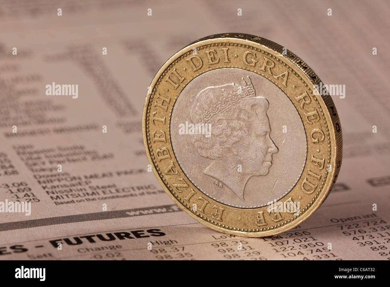 Regno Unito due pound coin in piedi sul bordo su uno sfondo di una pagina dal FT Foto Stock