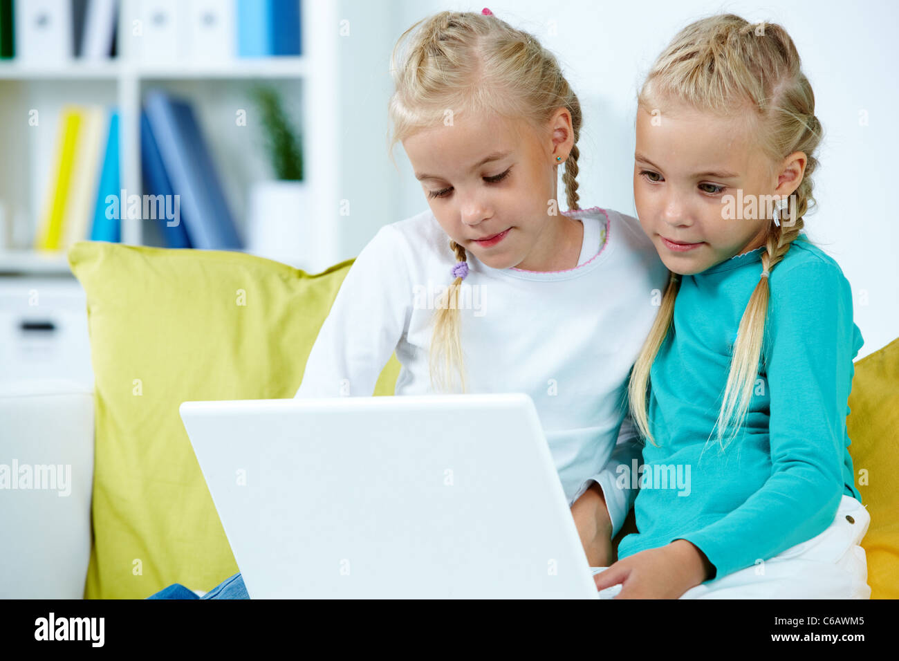 Ritratto di twin ragazze che studiano nella parte anteriore del computer portatile Foto Stock