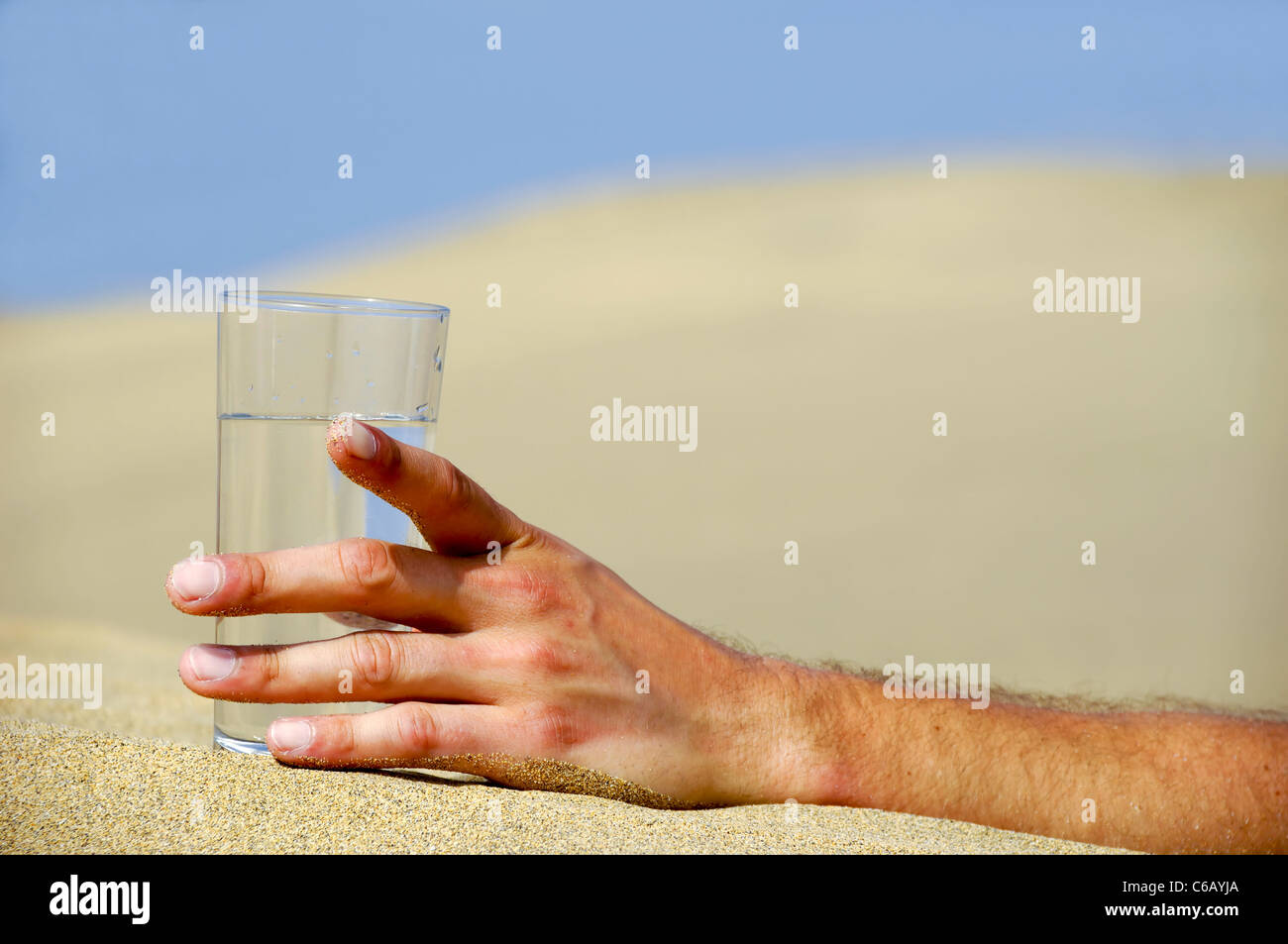 Mano è il raggiungimento di un fresco bicchiere di acqua fredda nel deserto. Foto Stock
