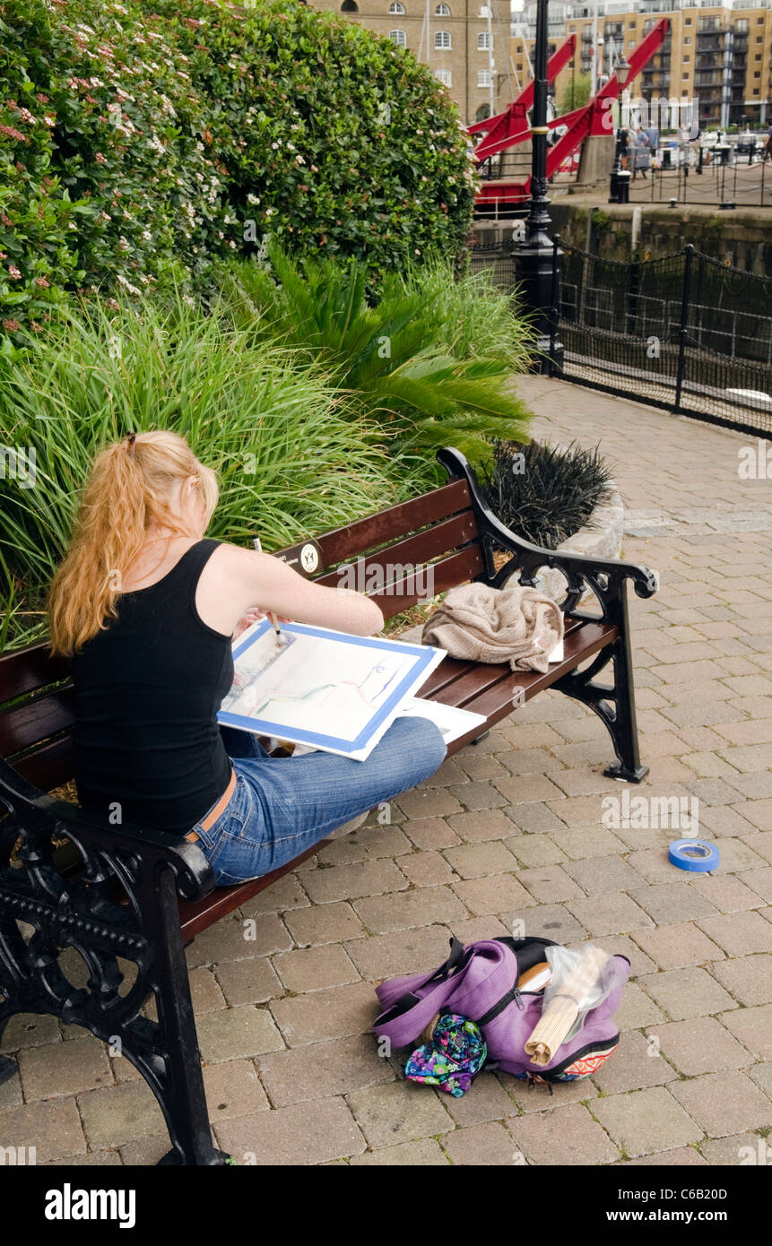 Un artista femminile dipingere un quadro di St Katharine Dock Londra REGNO UNITO Foto Stock