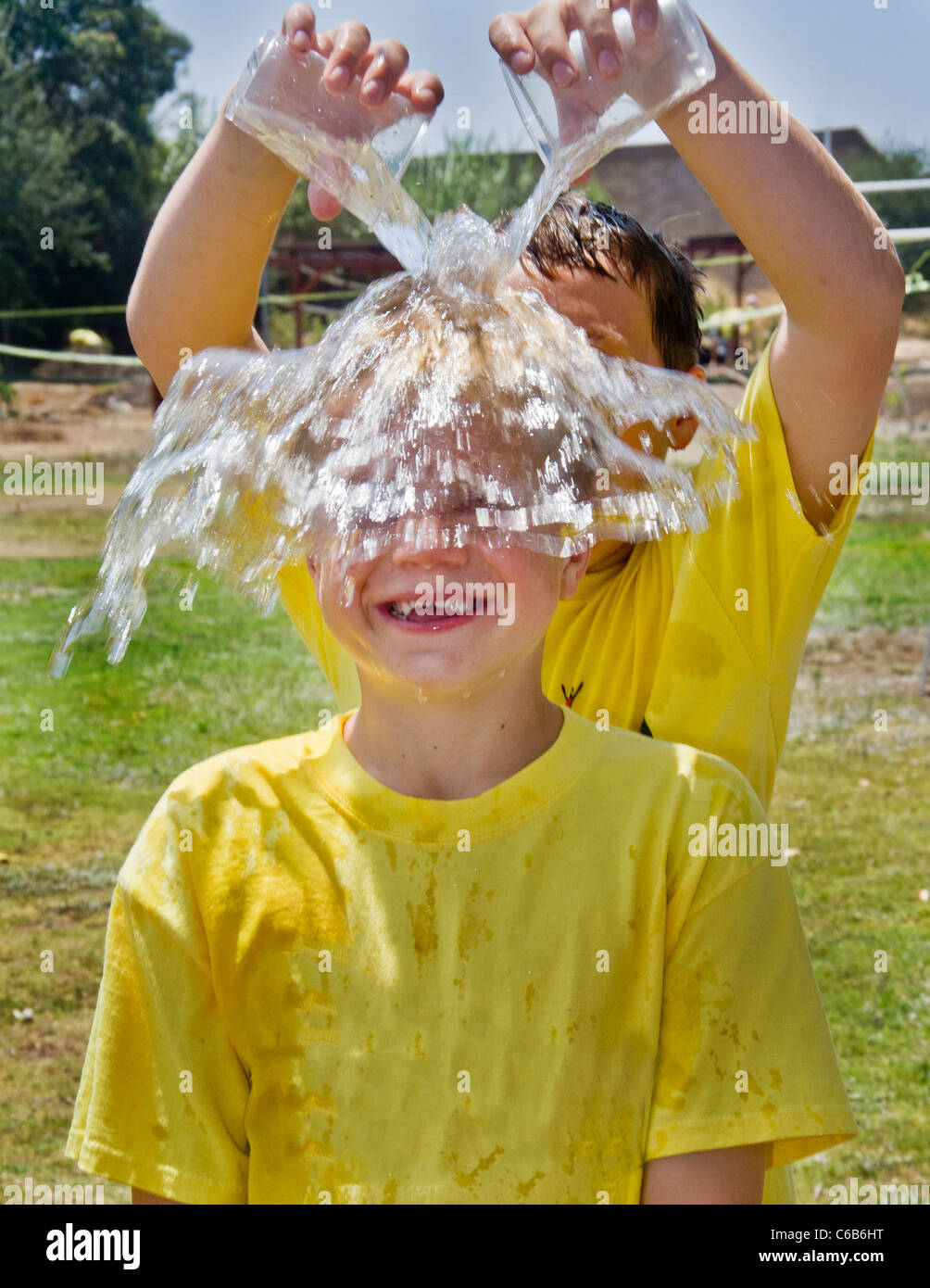 Un ragazzo preteen ha acqua fredda versata su se stesso in un pomeriggio caldo in arancione, CA. Foto Stock