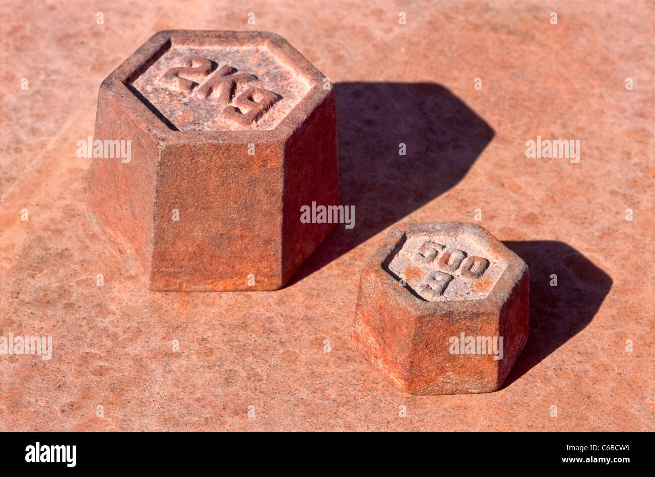 Due vecchie masse arrugginito una volta usato con una bilancia. Foto Stock