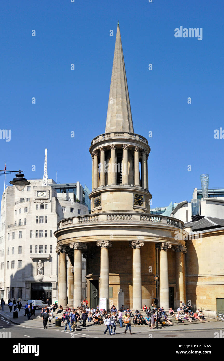 La gente seduta sui gradini di tutte le anime Chiesa Langham Place disegnato da John Nash BBC Broadcasting House al di là in Regent Street North London Inghilterra England Regno Unito Foto Stock