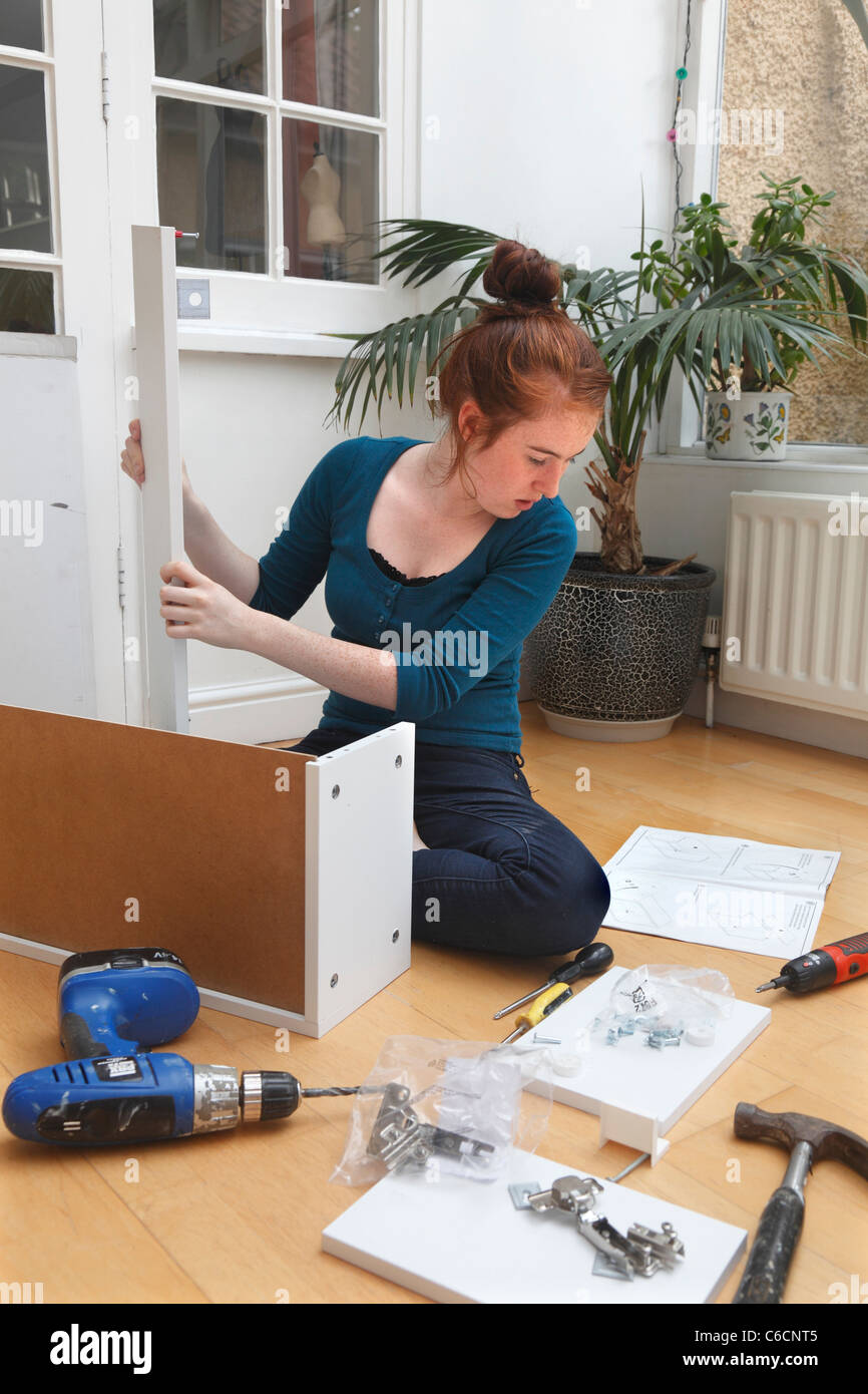 Ragazza giovane rendendo un armadio da un 'flat pack' kit DIY. Foto Stock