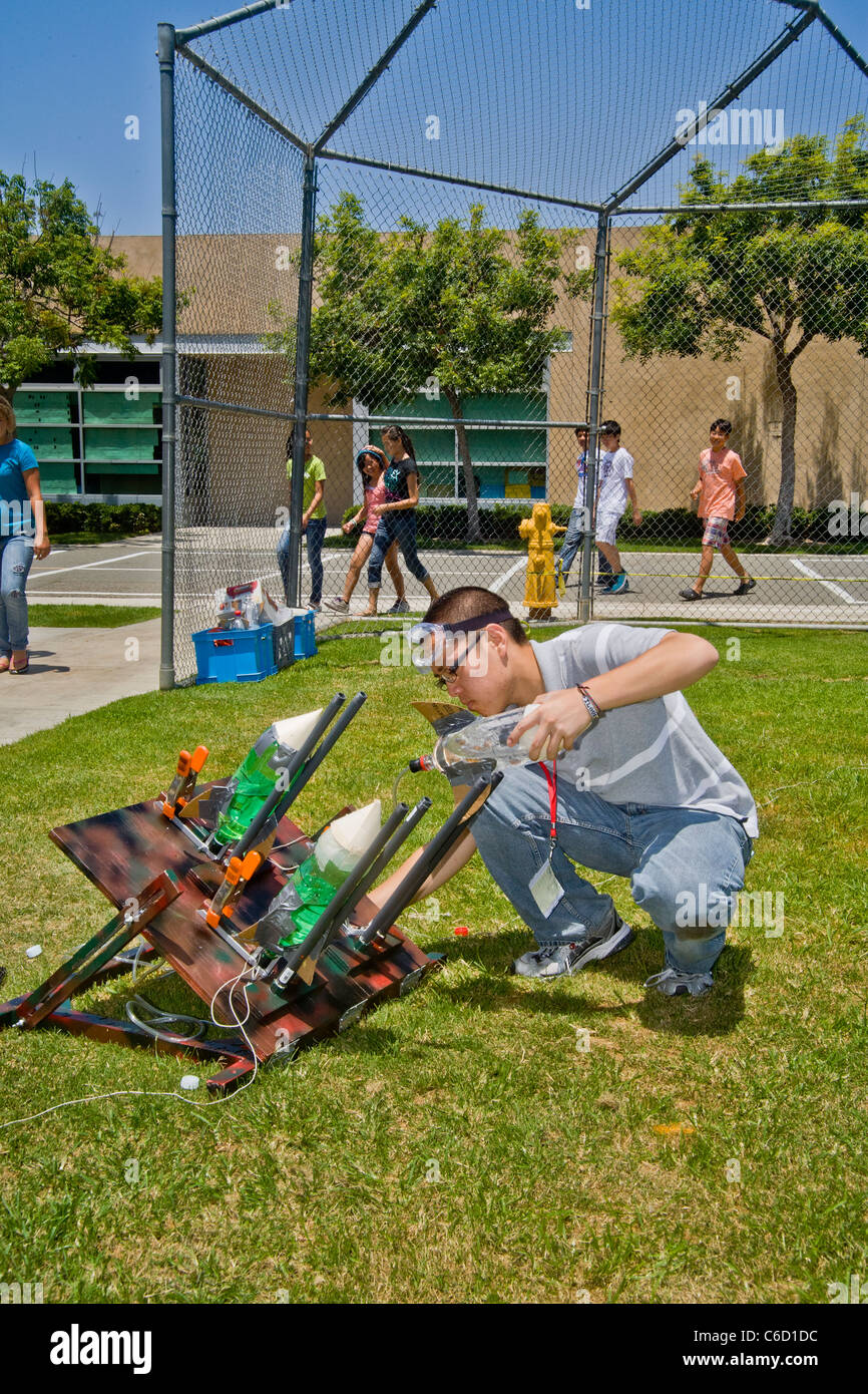 Un americano asiatico insegnante si prepara a lanciare un air-e-acqua-powered razzo bottiglia come parte di una scuola di scienza workshop. Foto Stock