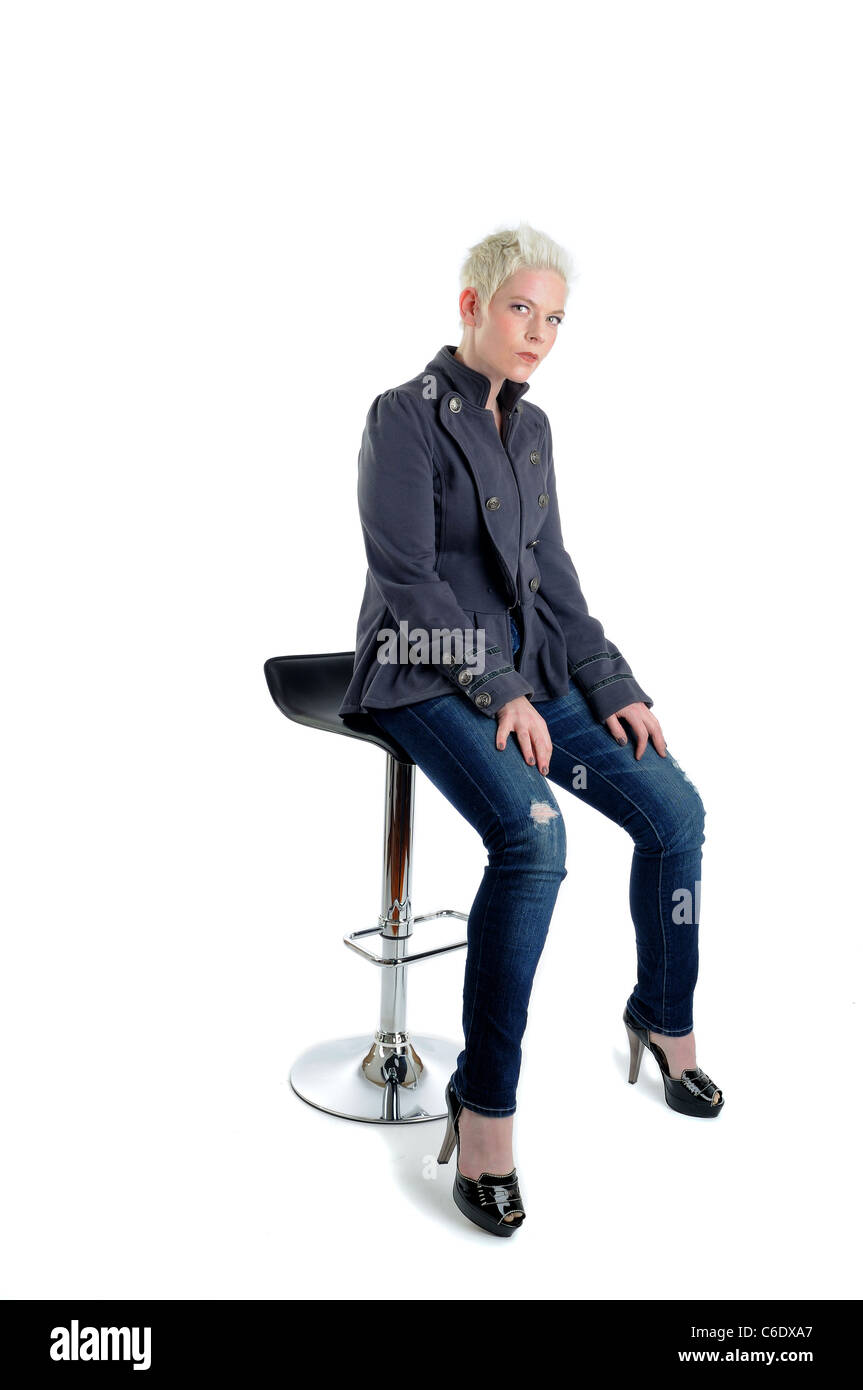 Breve dai capelli biondi donna seduto su un sgabello da bar Foto Stock