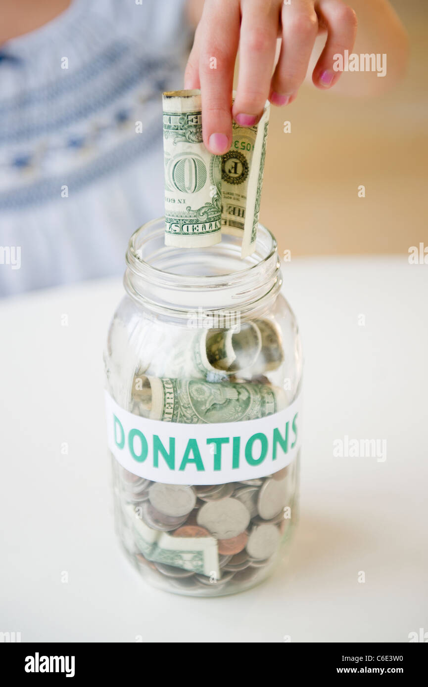 Stati Uniti d'America, New Jersey, Jersey City, la stretta di mano della ragazza mettendo dollaro in vaso Foto Stock