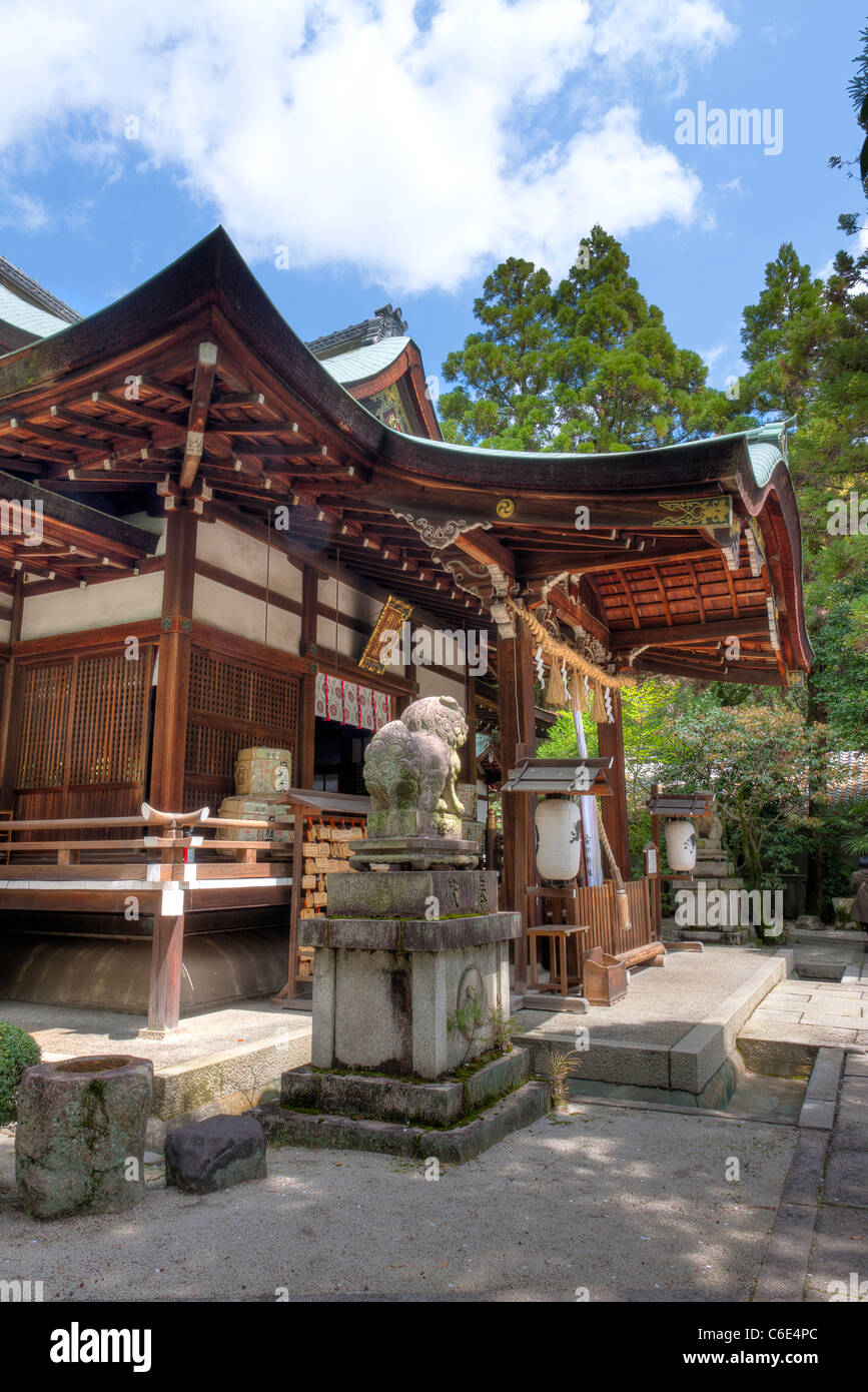 Vista laterale di un cane da leone, Komainu, statua custode e la sala principale vermilion del santuario Shinto Okazaki a Kyoto. Primavera con cielo blu. Foto Stock