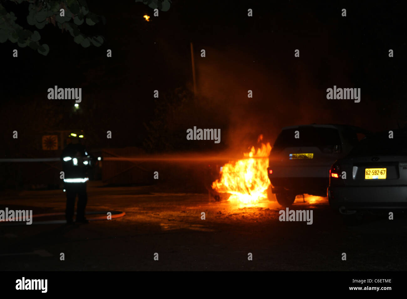 I pompieri spengono le fiamme in una vettura dopo un incidente Foto Stock