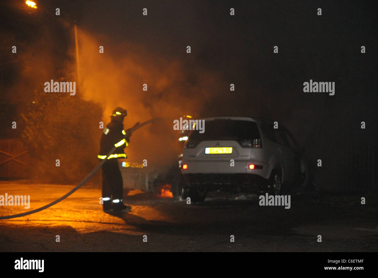 I pompieri spengono le fiamme in una vettura dopo un incidente Foto Stock