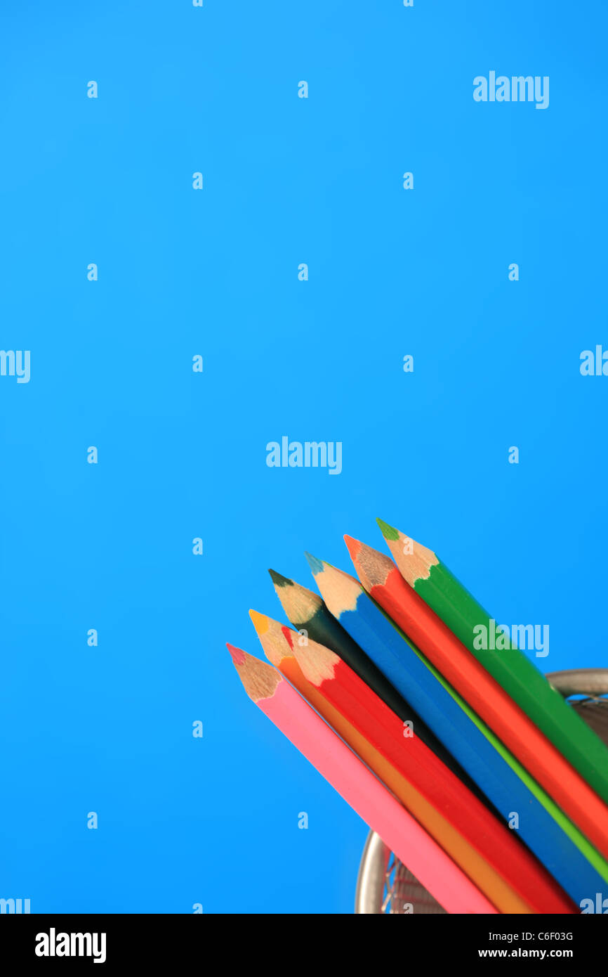 Multi matite colorate in una pentola, sfondo blu. Foto Stock