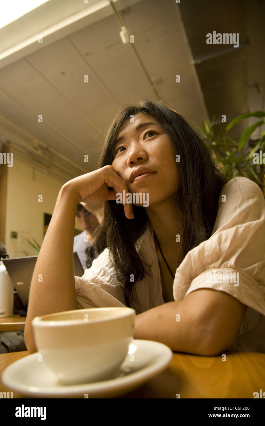 Giovane donna cinese da Pechino in Cina da soli in un bar durante la visita a New York City. Foto Stock
